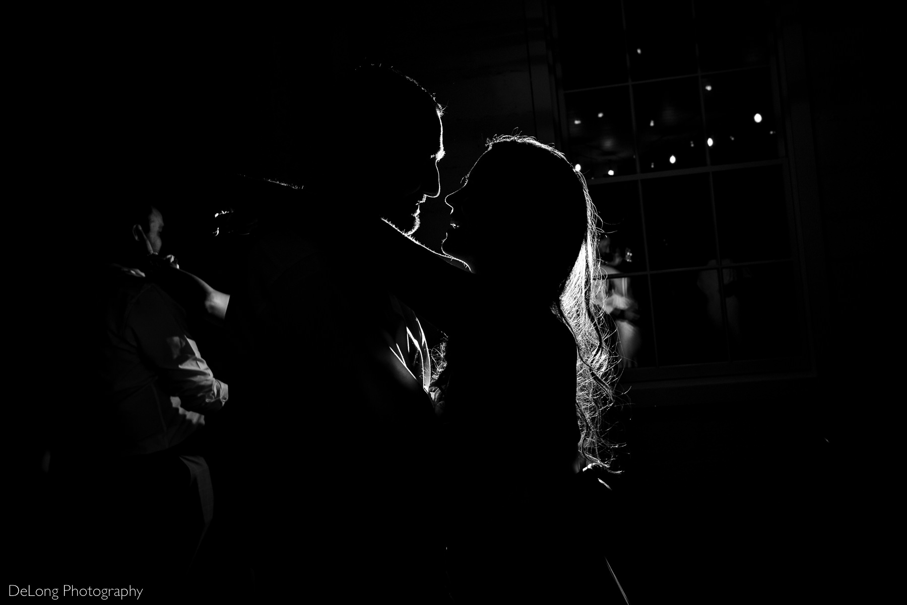 Black and white rim lit photograph of the bride and groom during their last dance at Upstairs Atlanta. Photograph by Charlotte wedding photographers DeLong Photography.