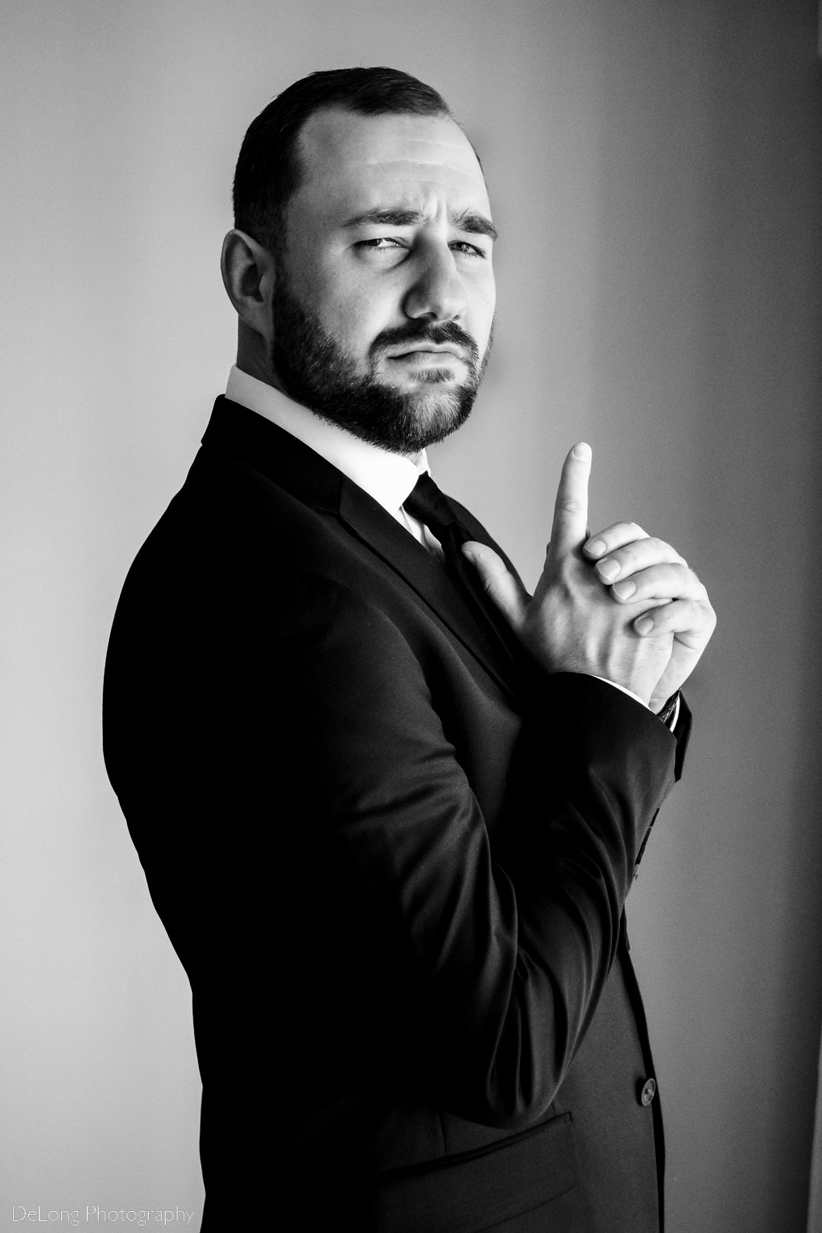 Black and white photograph of groom being silly and posing with a finger gun and serious expression by Charlotte wedding photographers DeLong Photography