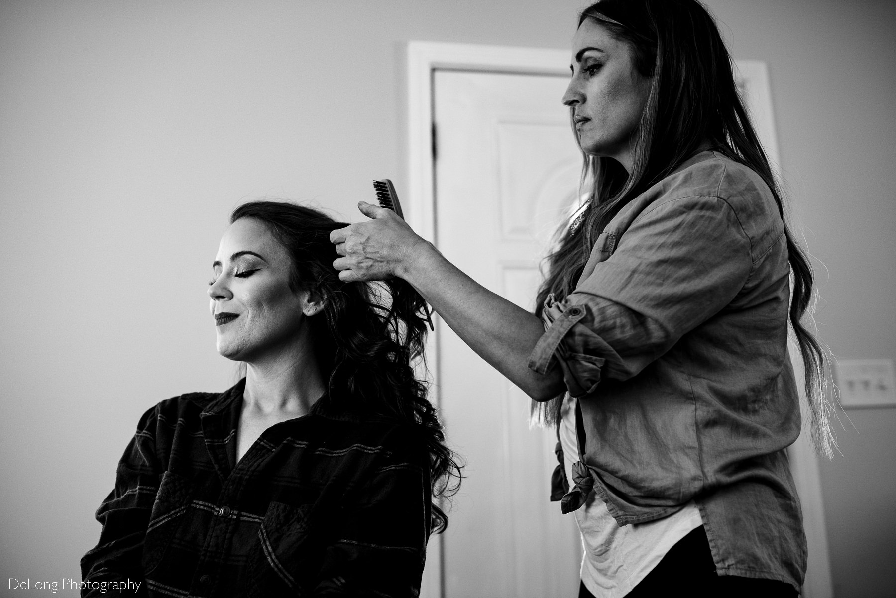 Black and white photograph of a bridge getting her hair done on her wedding day by Charlotte wedding photographers DeLong Photography