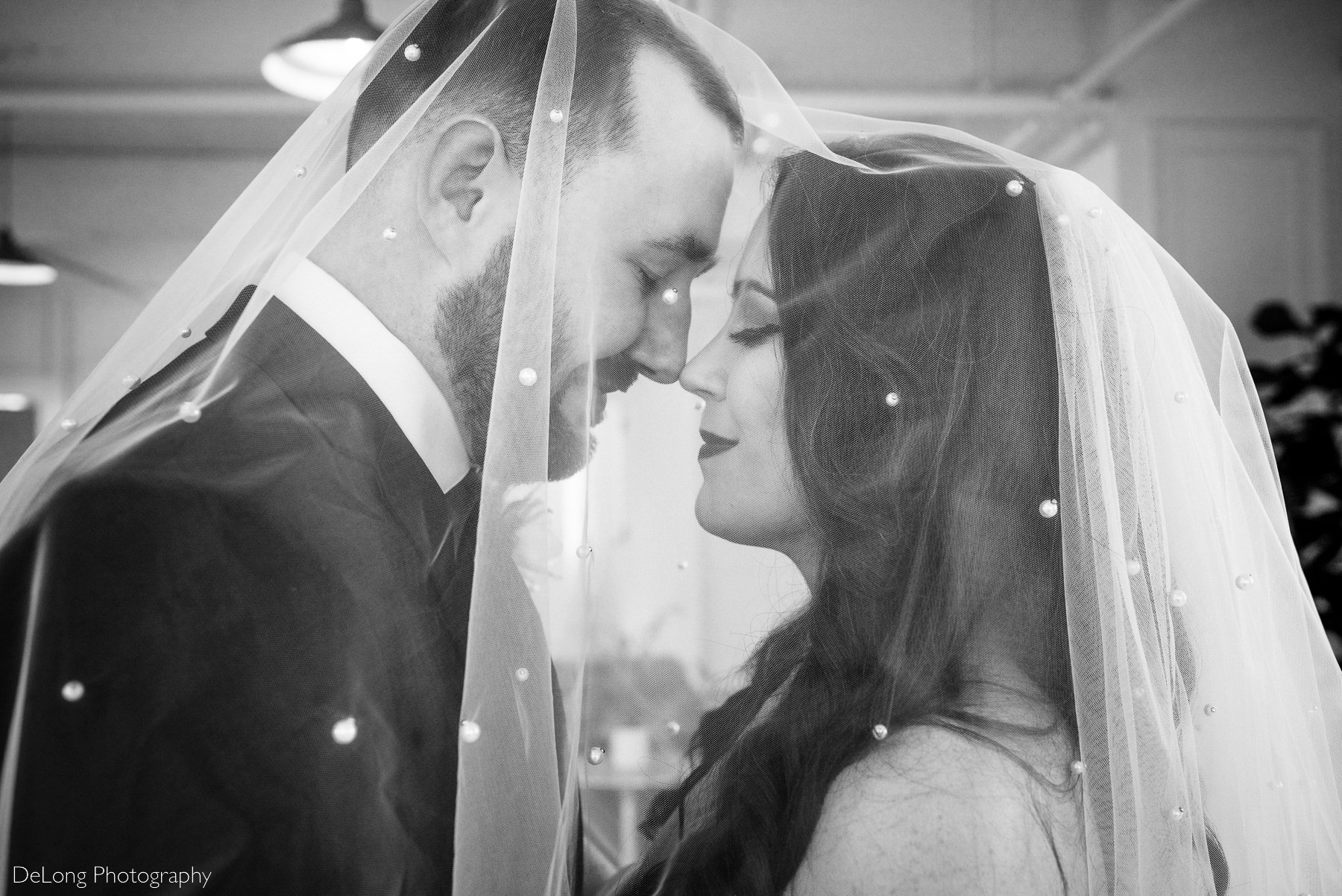 Black and white photograph of bride and groom sharing a quite moment together under her veil with their eyes closed inside Upstairs Atlanta. Photograph by Charlotte wedding photographers DeLong Photography