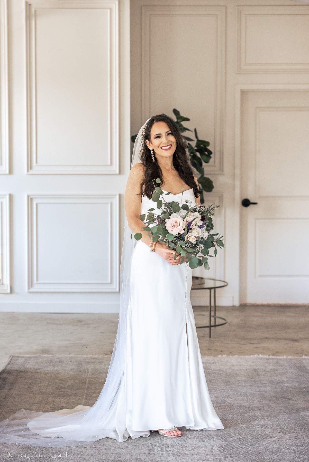 Traditional bridal portrait where the bride is holding her bouquet and smiling directly at the camera, inside Upstairs Atlanta. Photograph by Charlotte wedding photographers DeLong Photography.