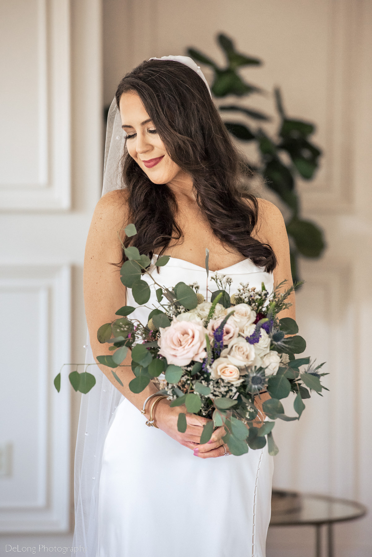 Bridal portrait where the bride is looking down and to her right, holding her bouquet, inside Upstairs Atlanta. Photograph by Charlotte wedding photographers DeLong Photography.