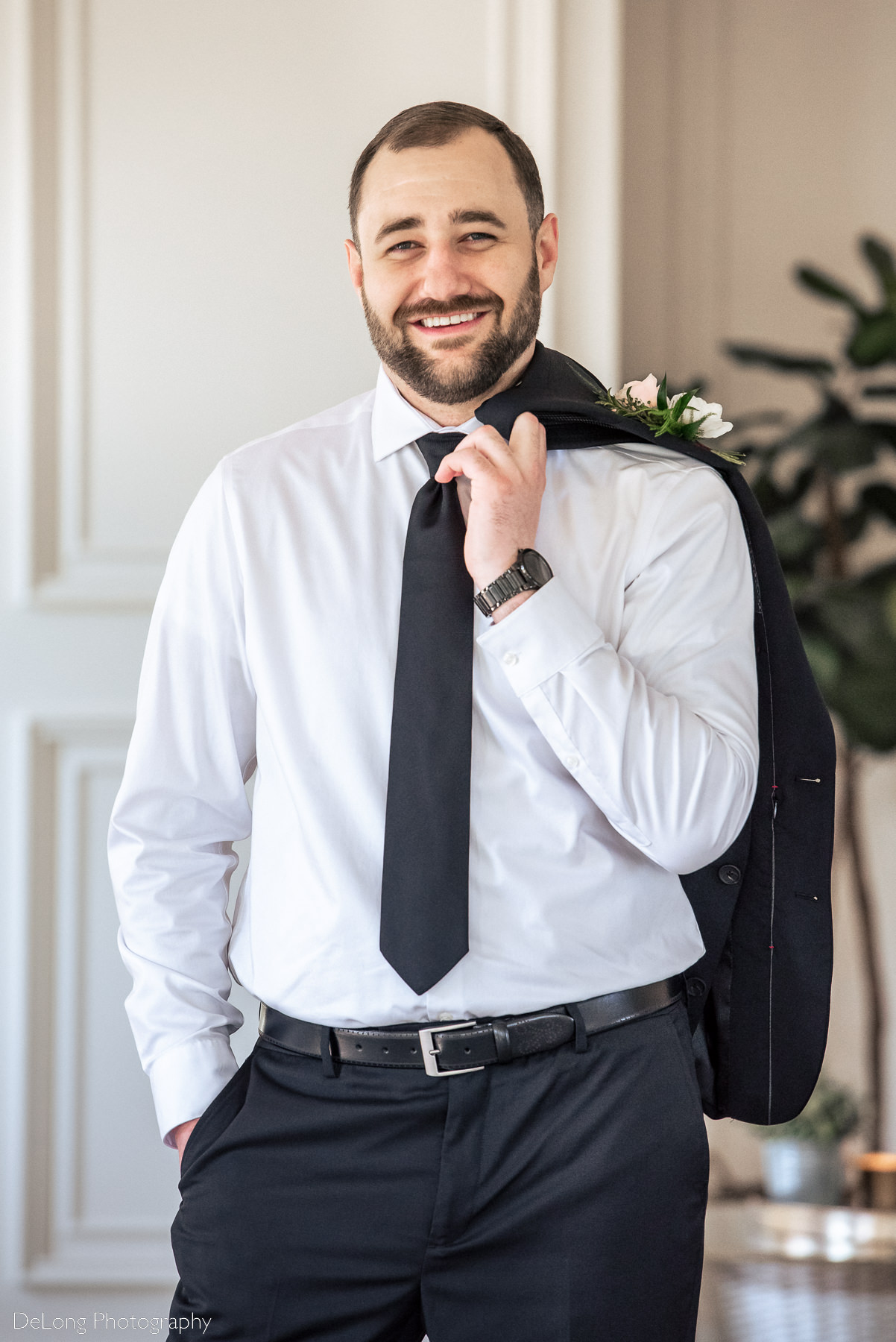 Three-quarter crop casual groom portrait with his jacket over his shoulder, insider Upstairs Atlanta. Photograph by Charlotte wedding photographers DeLong Photography.