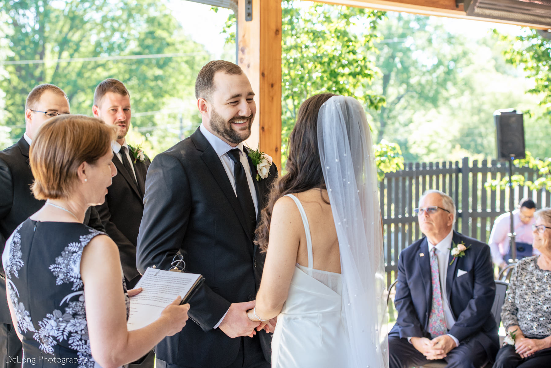 Groom giggling during the ceremony taking his bride's hands for the first time. Photograph by Charlotte wedding photographers DeLong Photography.