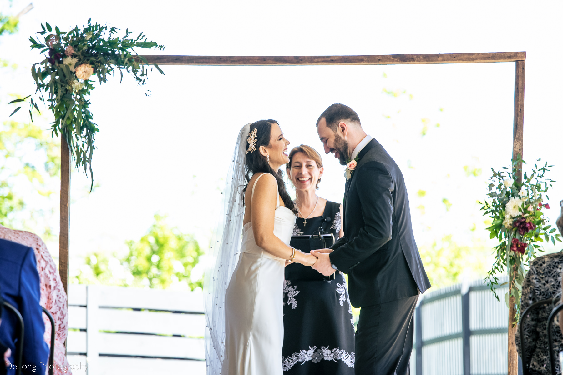 Bride and groom cracking up laughing during their wedding ceremony. Photograph by Charlotte wedding photographers DeLong Photography.