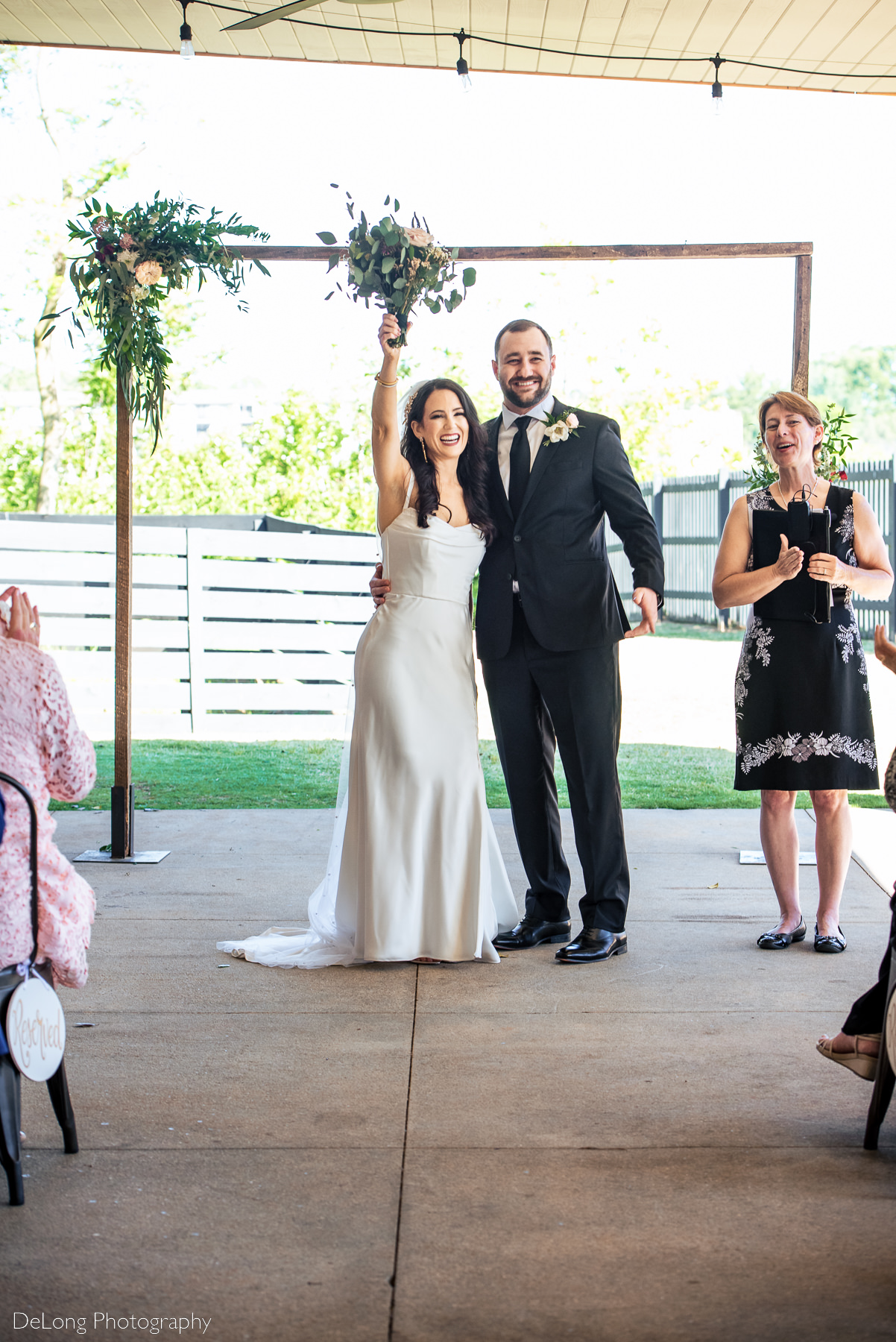 Bride and groom celebrating with their hands in the air at the end of their wedding ceremony. Photograph by Charlotte wedding photographers DeLong Photography.