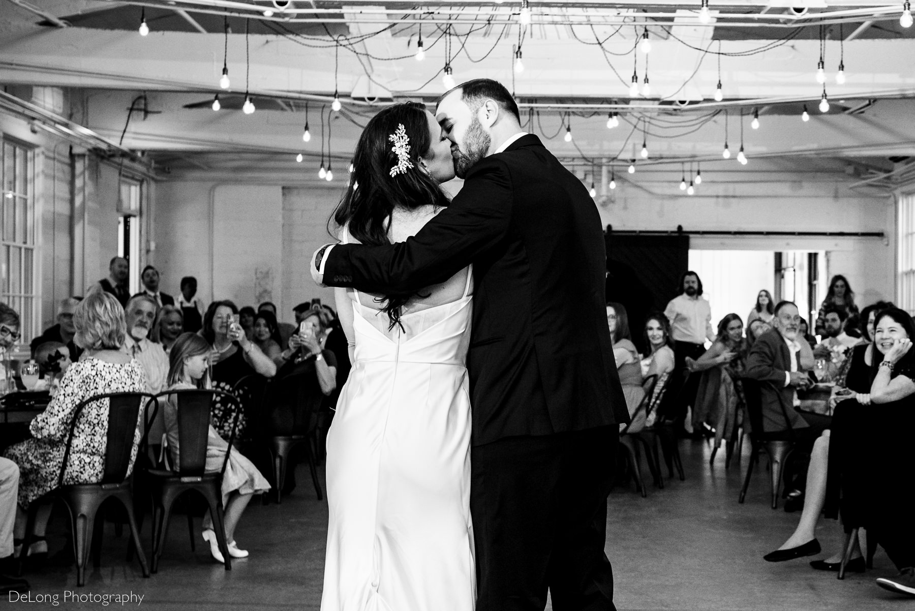 Black and white photograph of a bride and groom kissing during their first dance at Upstairs Atlanta. Photograph by Charlotte wedding photographers DeLong Photography.