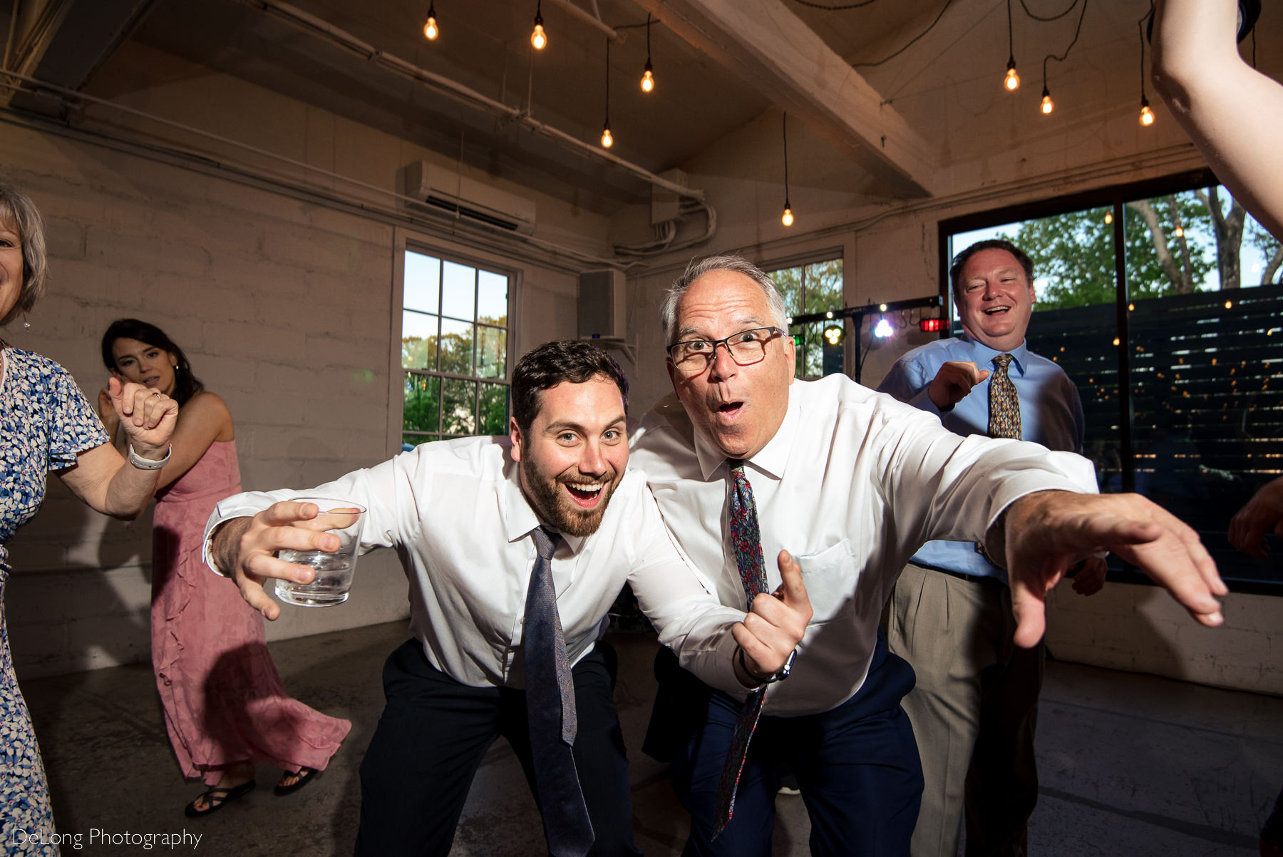 Up close candid photograph of guests having fun on the dance floor during wedding reception at Upstairs Atlanta. Photograph by Charlotte wedding photographers DeLong Photography.