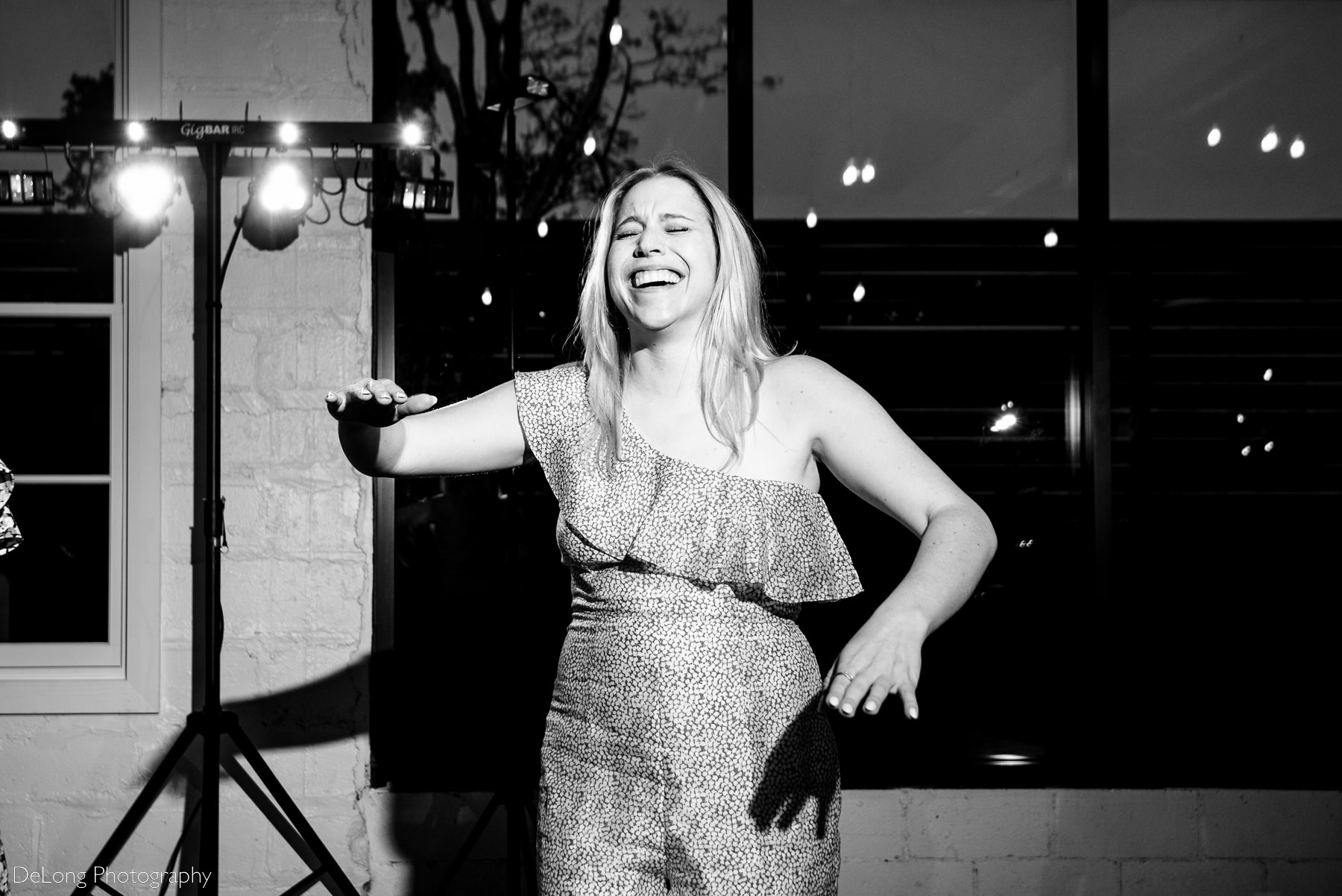 Black and white photograph of a guest cracking up while dancing on the dance floor of Upstairs Atlanta. Photograph by Charlotte wedding photographers DeLong Photography.