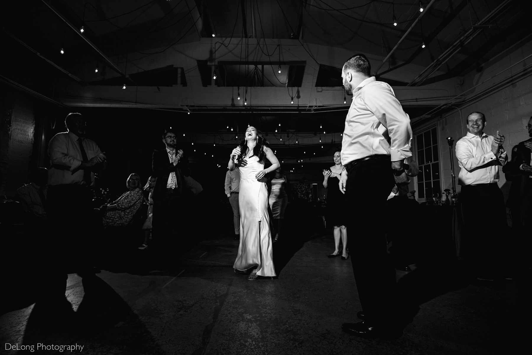 Bride bursting into laughing as her groom dances in a silly way on the dance floor of Upstairs Atlanta. Photograph by Charlotte wedding photographers DeLong Photography. 