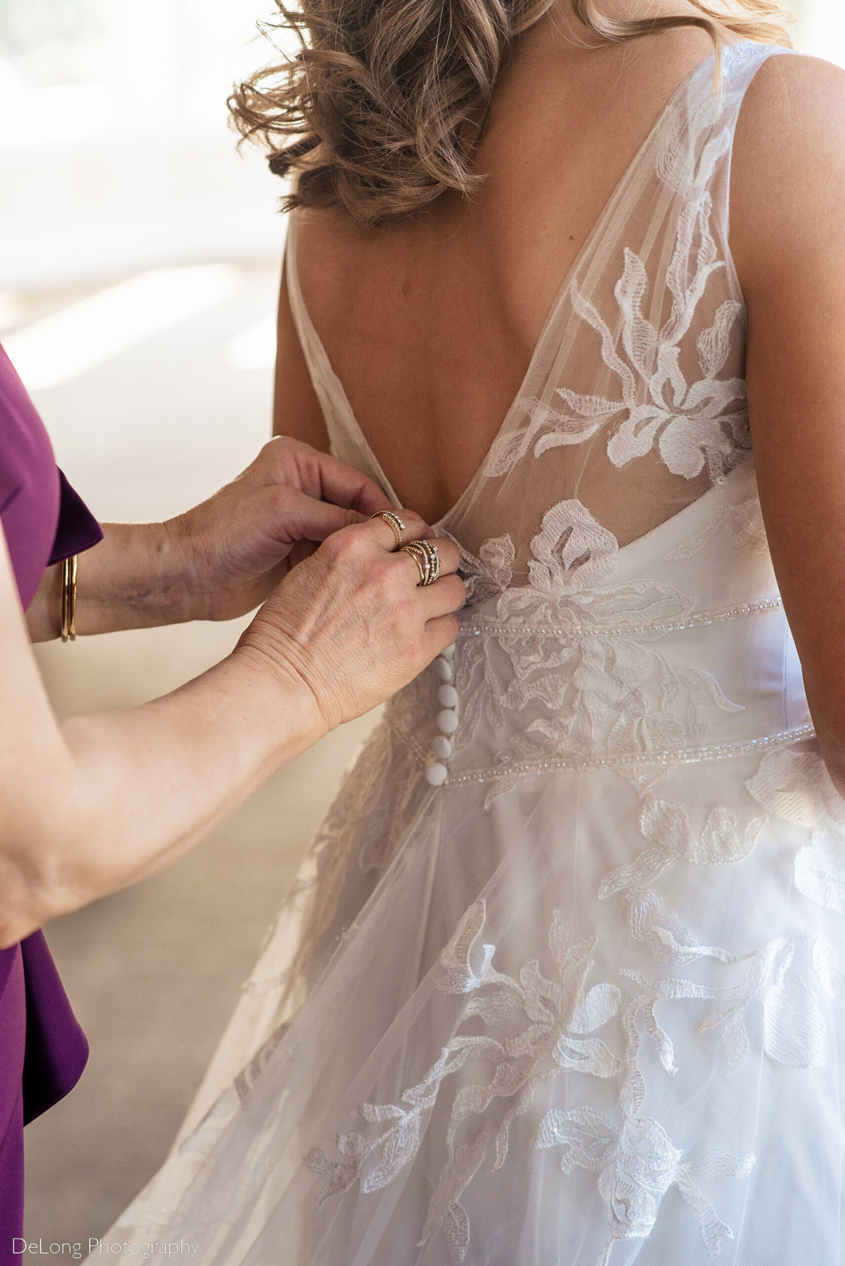 Up close photograph of bride having her wedding dress buttoned by her mother at Pine Island Country Club in Charlotte, NC by Charlotte wedding Photographers DeLong Photography