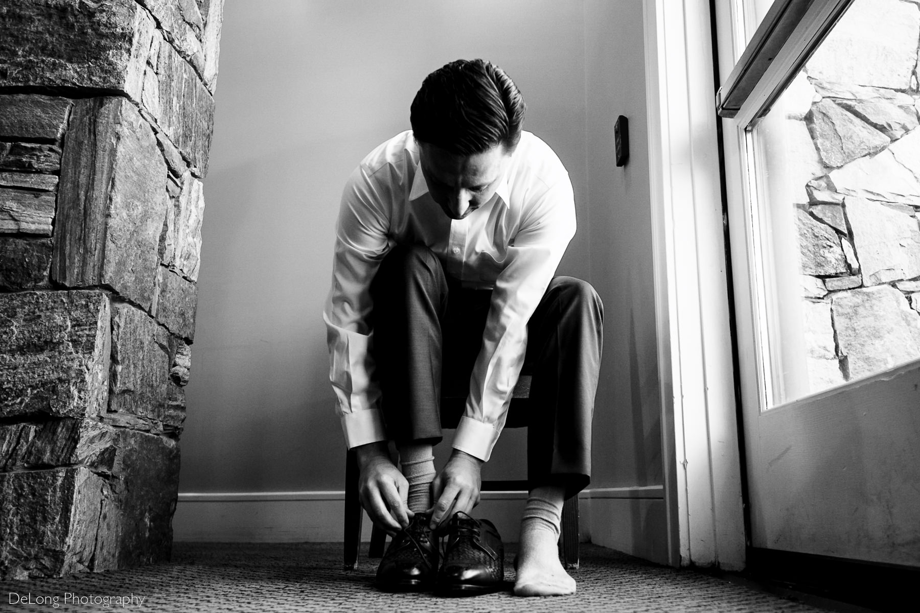 Black and white image of groom putting on his shoes at Pine Island Country Club in Charlotte, NC by Charlotte wedding Photographers DeLong Photography