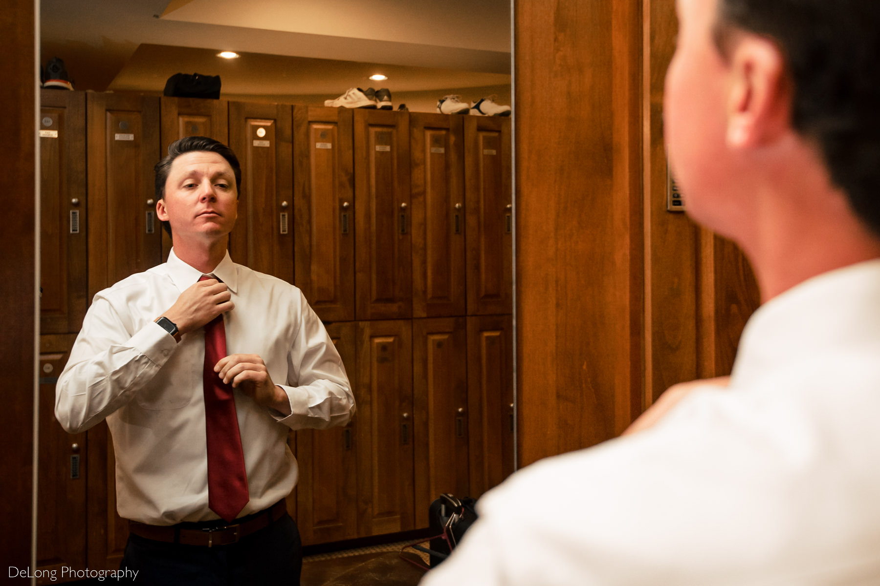 Groom putting on his burgundy tie before his wedding at Pine Island Country Club in Charlotte, NC by Charlotte wedding Photographers DeLong Photography