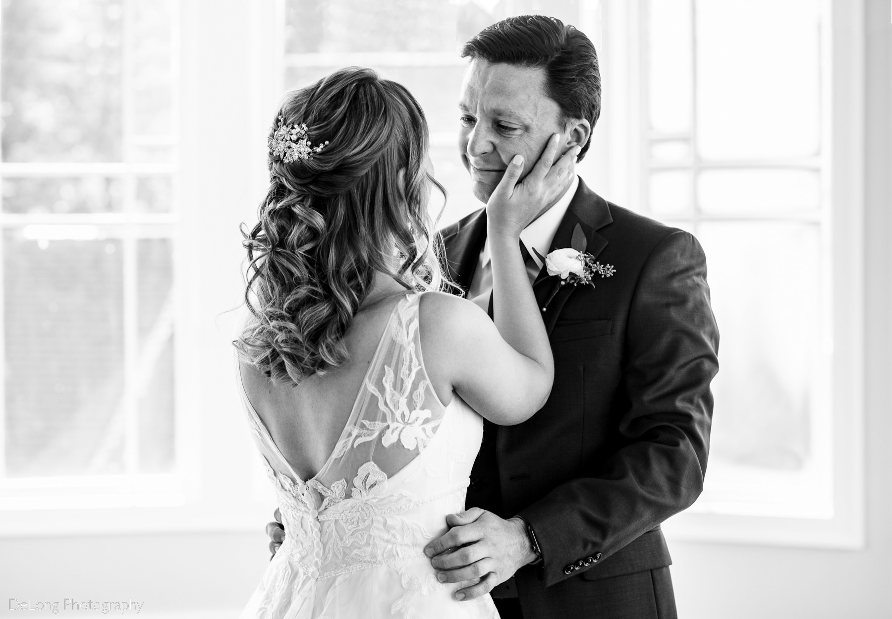 Black and white photograph of bride holding her groom's face as he cries happy tears during their first look at Pine Island Country Club in Charlotte, NC by Charlotte wedding Photographers DeLong Photography