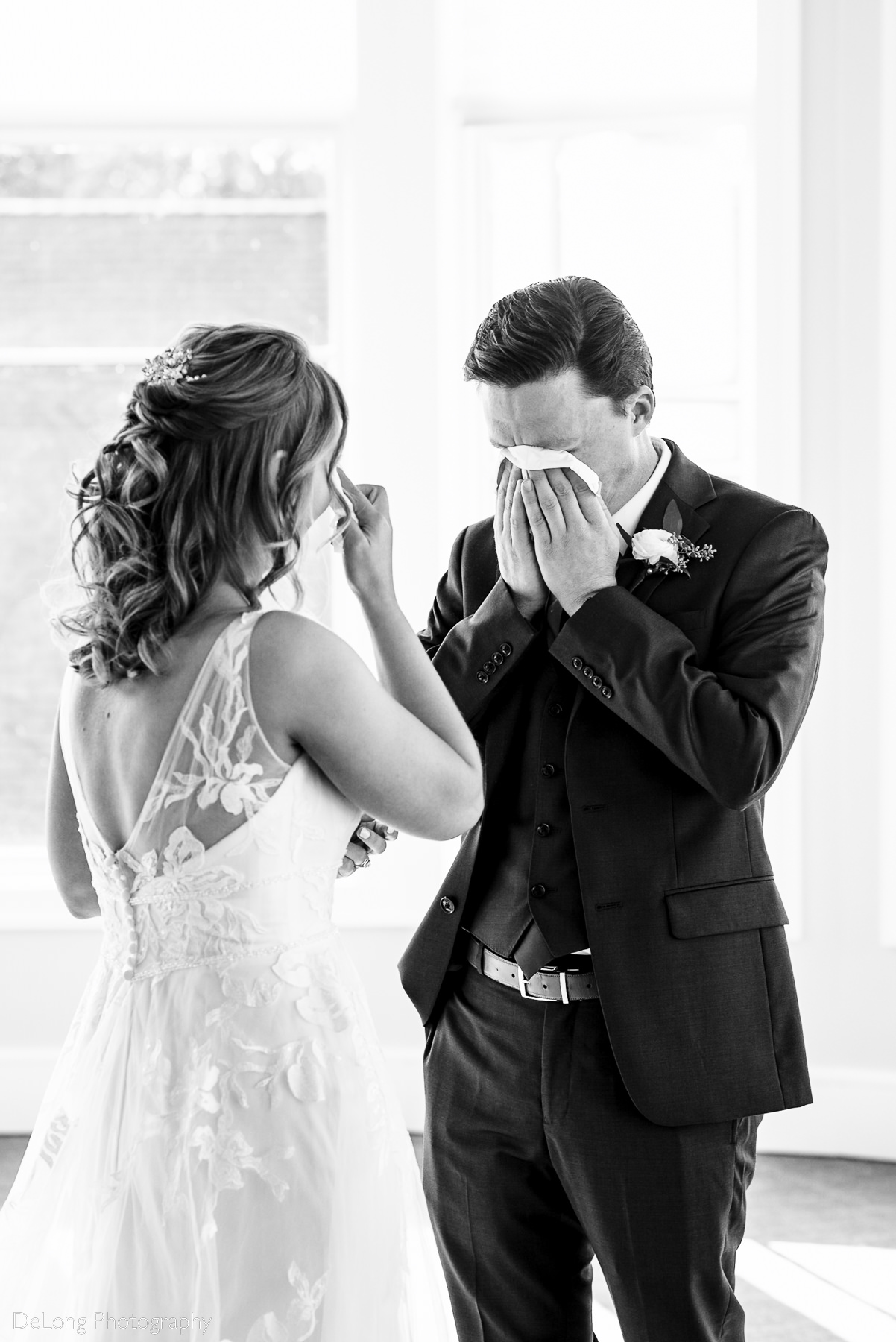 Black and white photograph of both the bride and groom wiping their tears after a happy and emotional first look at Pine Island Country Club in Charlotte, NC by Charlotte wedding Photographers DeLong Photography