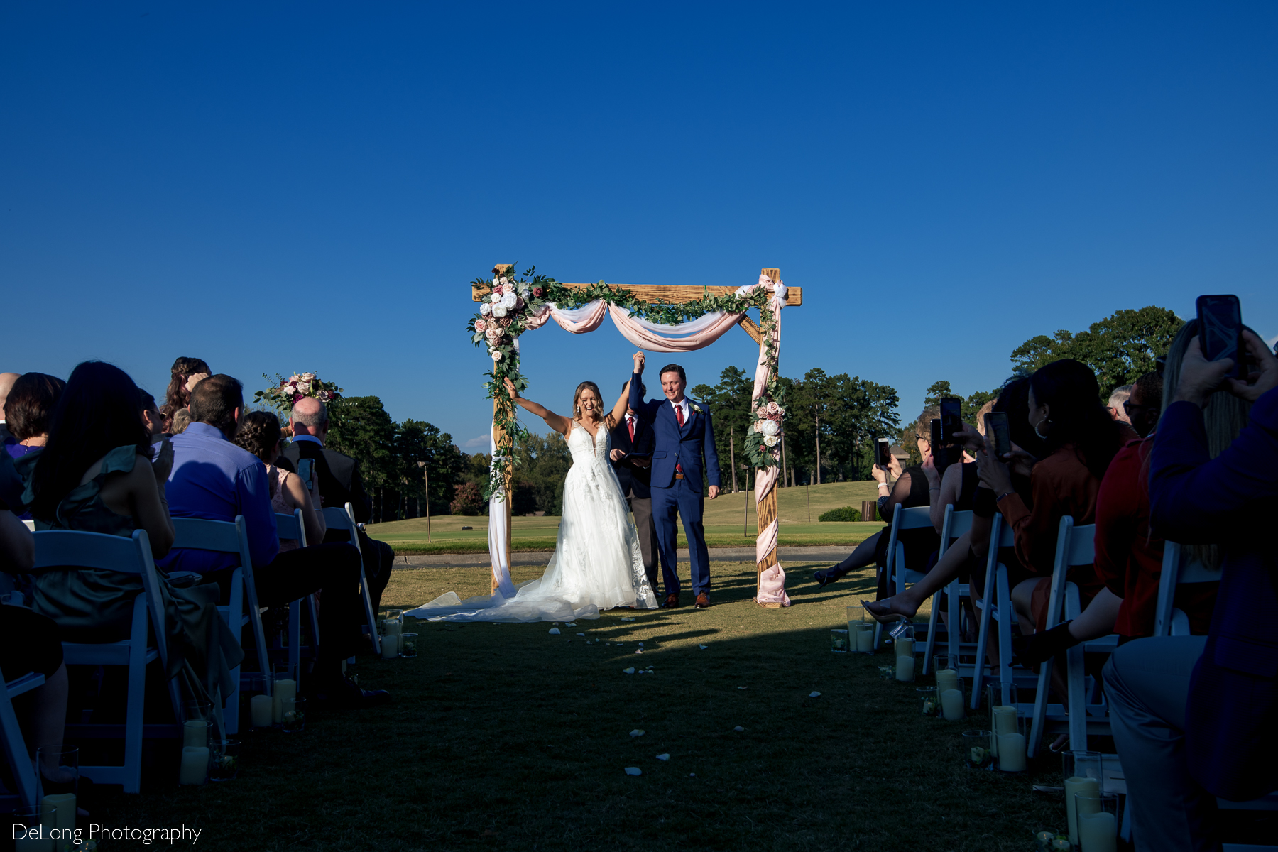 Bride and groom cheering with joy being announced as husband and wife during their ceremony at Pine Island Country Club by Charlotte wedding photographers DeLong Photography