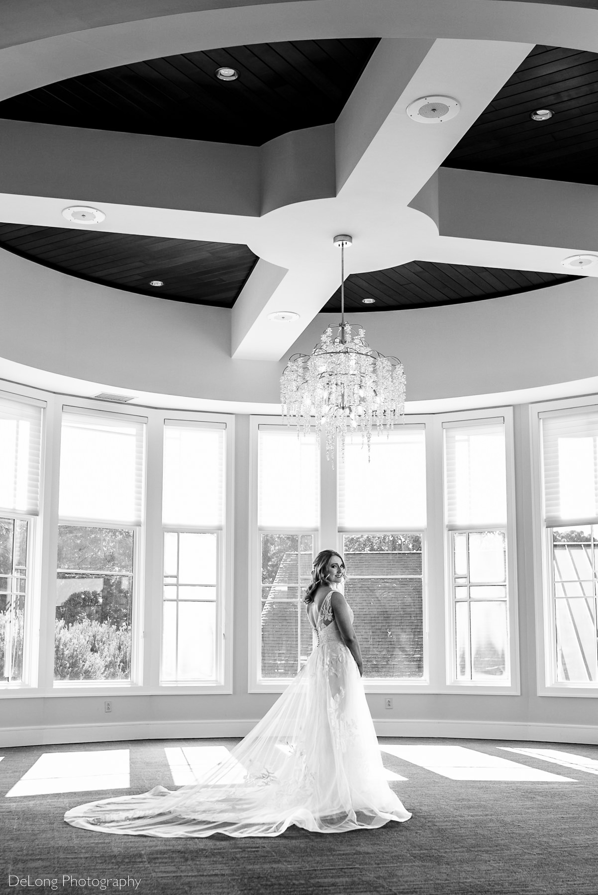 Black and white bridal portrait showing off the train and back of her wedding dress at Pine Island Country Club in Charlotte, NC by Charlotte wedding Photographers DeLong Photography