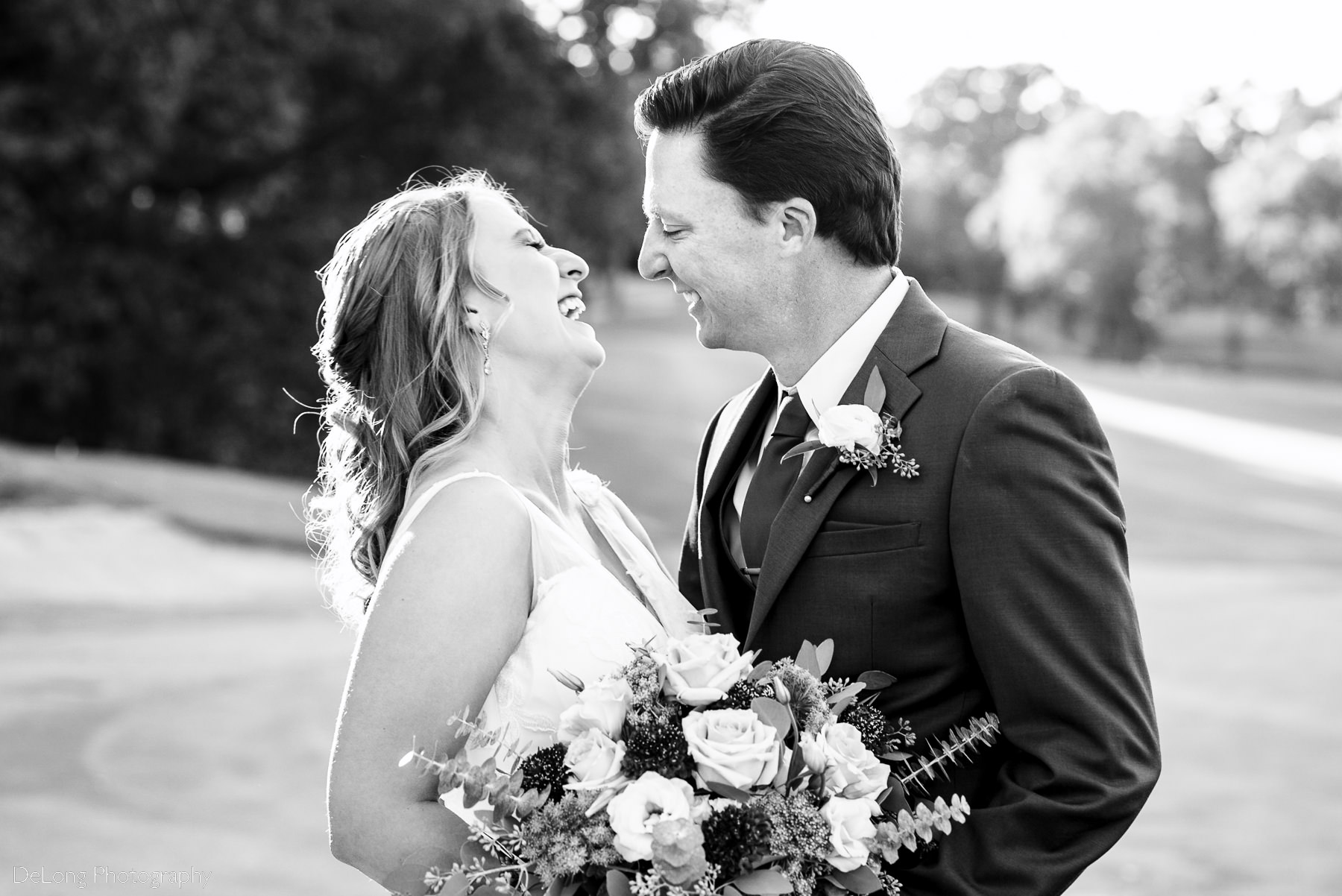 Black and white photograph of candid laughter between the bride and groom at Pine Island Country Club in Charlotte, NC by Charlotte wedding Photographers DeLong Photography