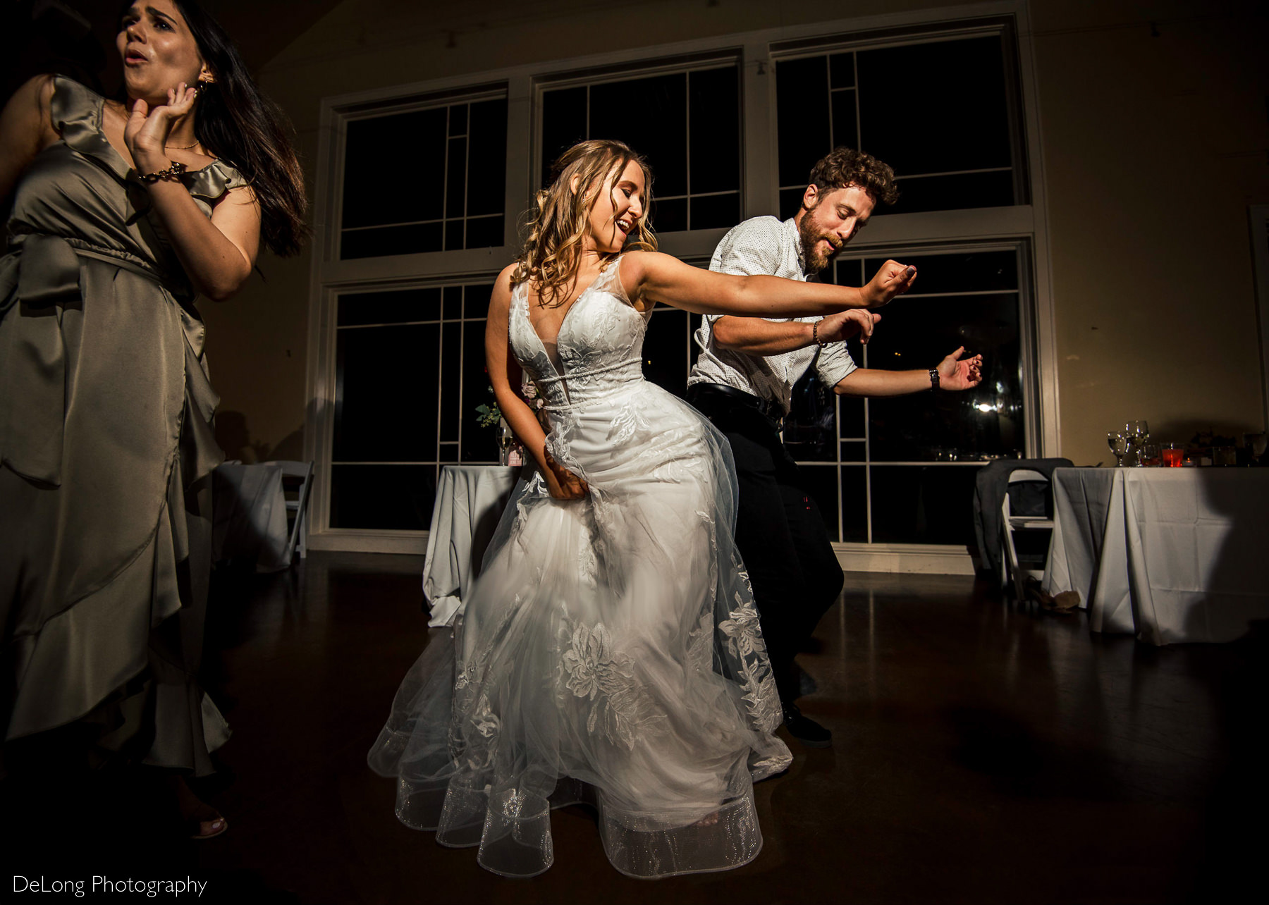 Bride and a guest having fun dancing hip-to-hip on the dance floor at Pine Island Country Club in Charlotte, NC by Charlotte wedding Photographers DeLong Photography