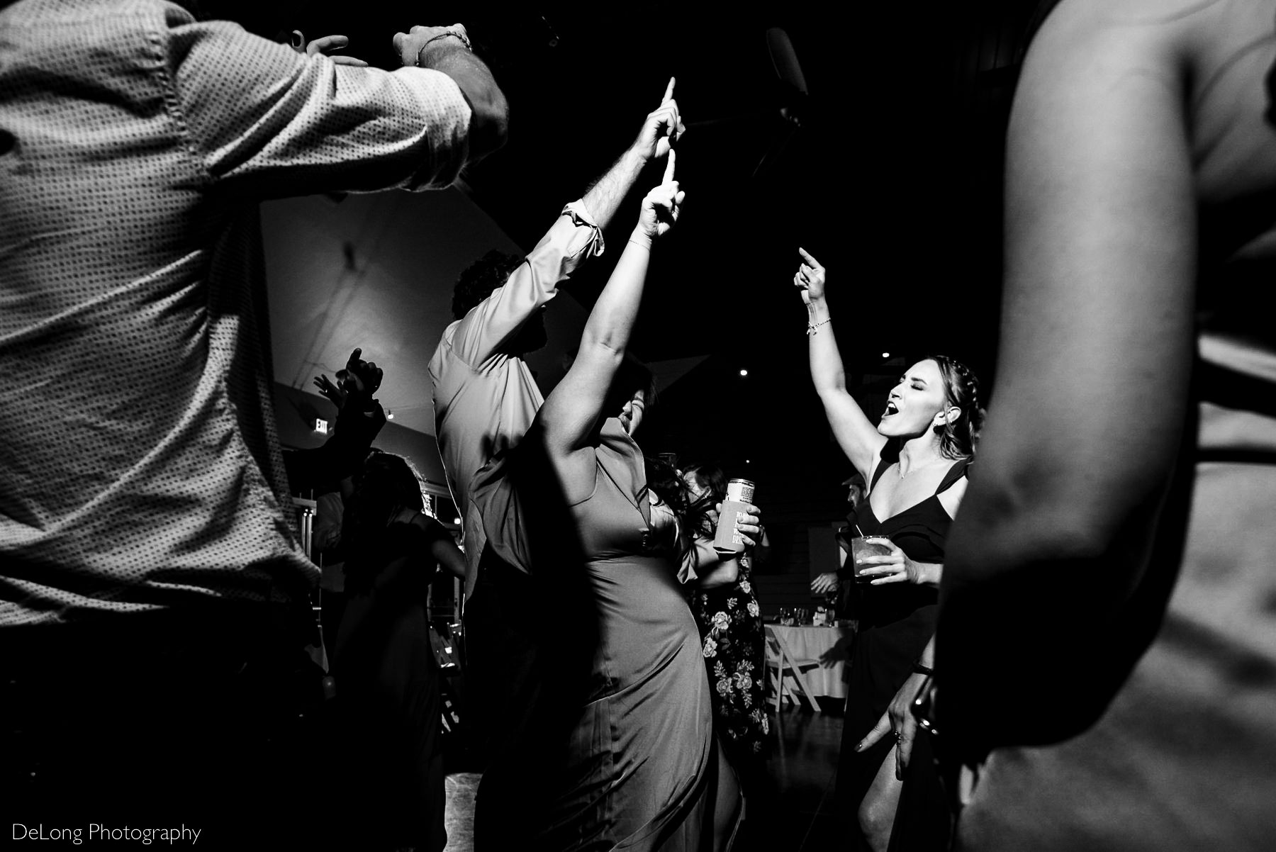 Black and white image of guests singing and pointing upward at Pine Island Country Club in Charlotte, NC by Charlotte wedding Photographers DeLong Photography