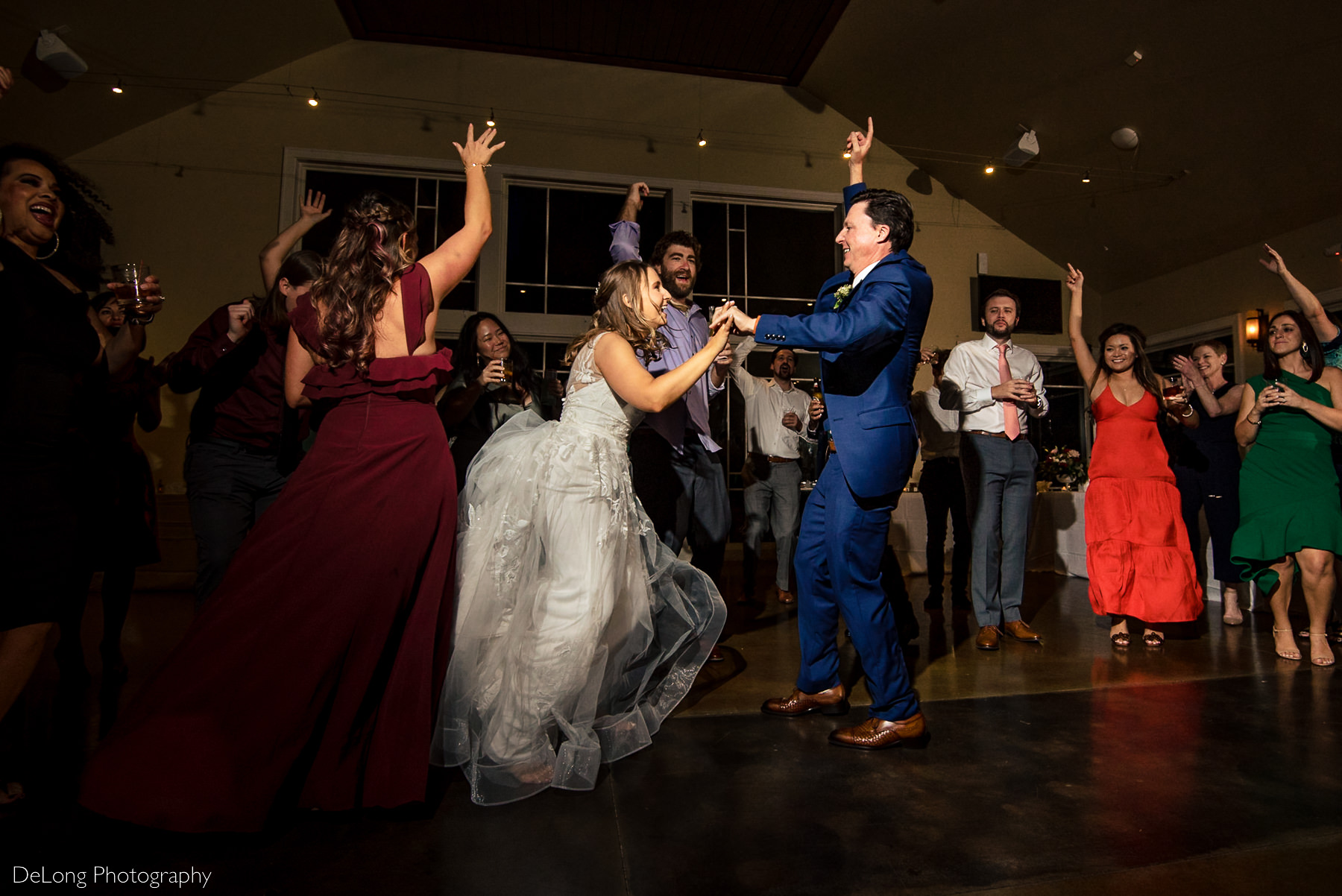 Bride and groom smiling and laughing on the dance floor surrounded by their guests at Pine Island Country Club in Charlotte, NC by Charlotte wedding Photographers DeLong Photography