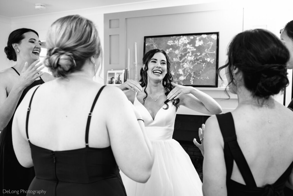 black and white image of bride crying and smiling among her bridesmaids during a bridesmaids first look by Charlotte wedding photographers DeLong Photography