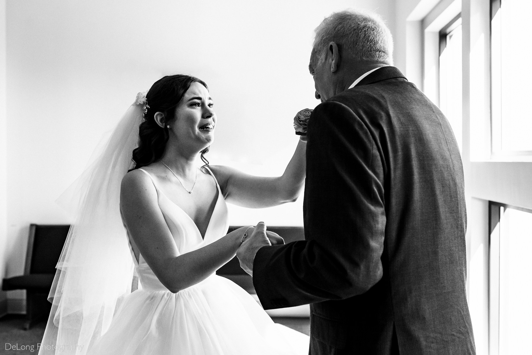 Crying daughter as father kisses her hands during their first look at St Gabriel Catholic Church in Charlotte, NC by Charlotte wedding photographers DeLong Photography