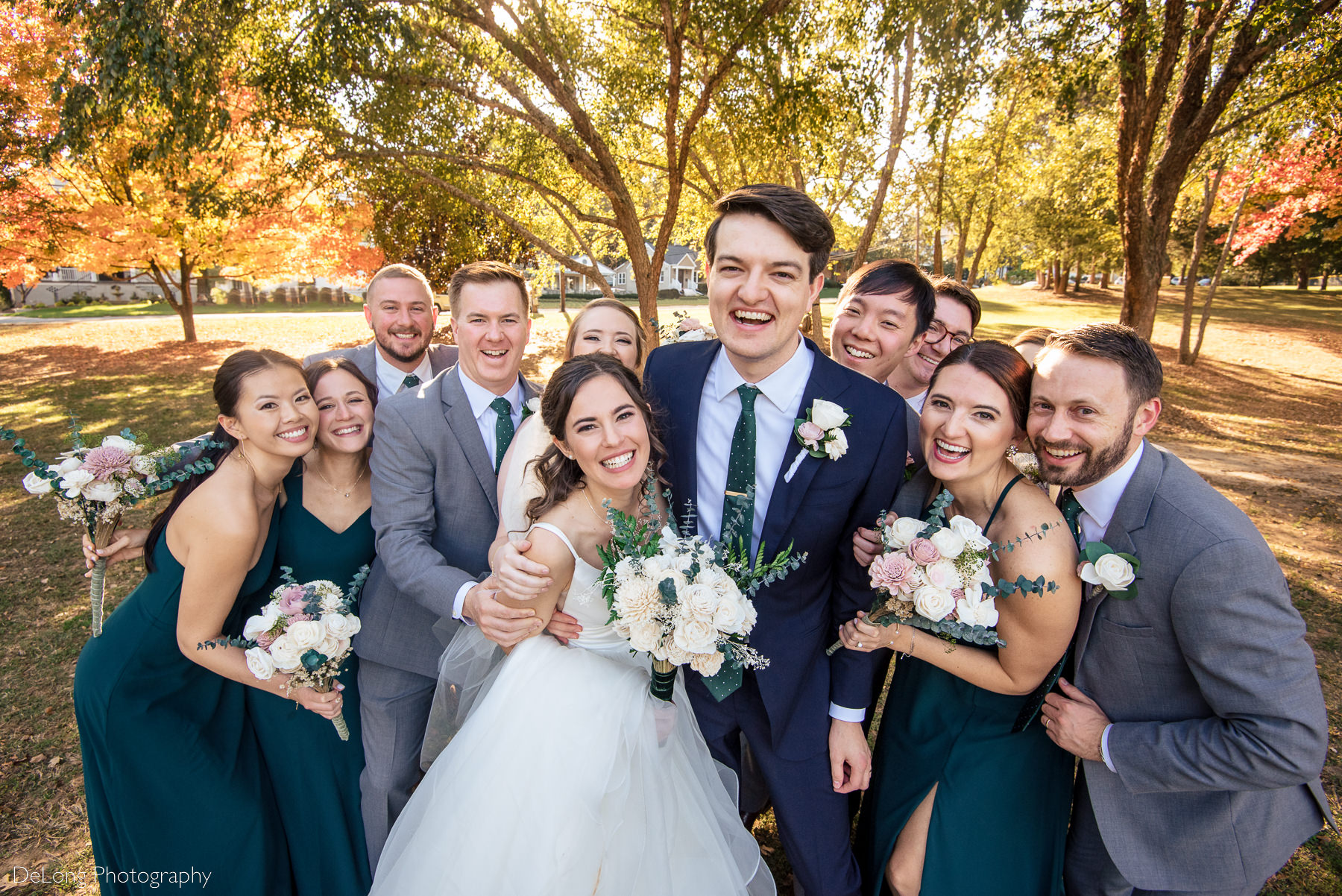 Raised view of bride and groom and their wedding party squeezing in for a big hug at Freedom Park in Charlotte, NC by Charlotte wedding photographers DeLong Photography