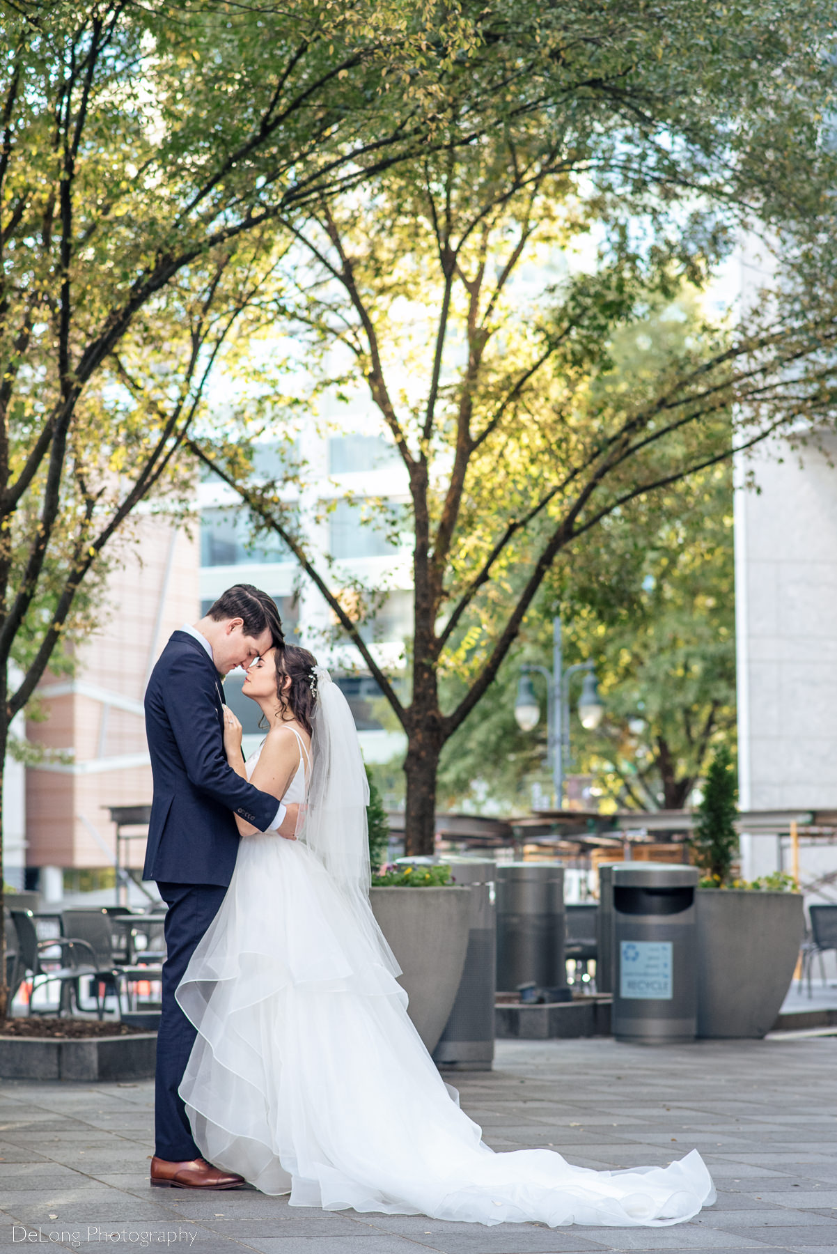 Bride and groom sharing a soft serious moment with their foreheads together outside the Mint Museum Uptown by Charlotte wedding photographers DeLong Photography