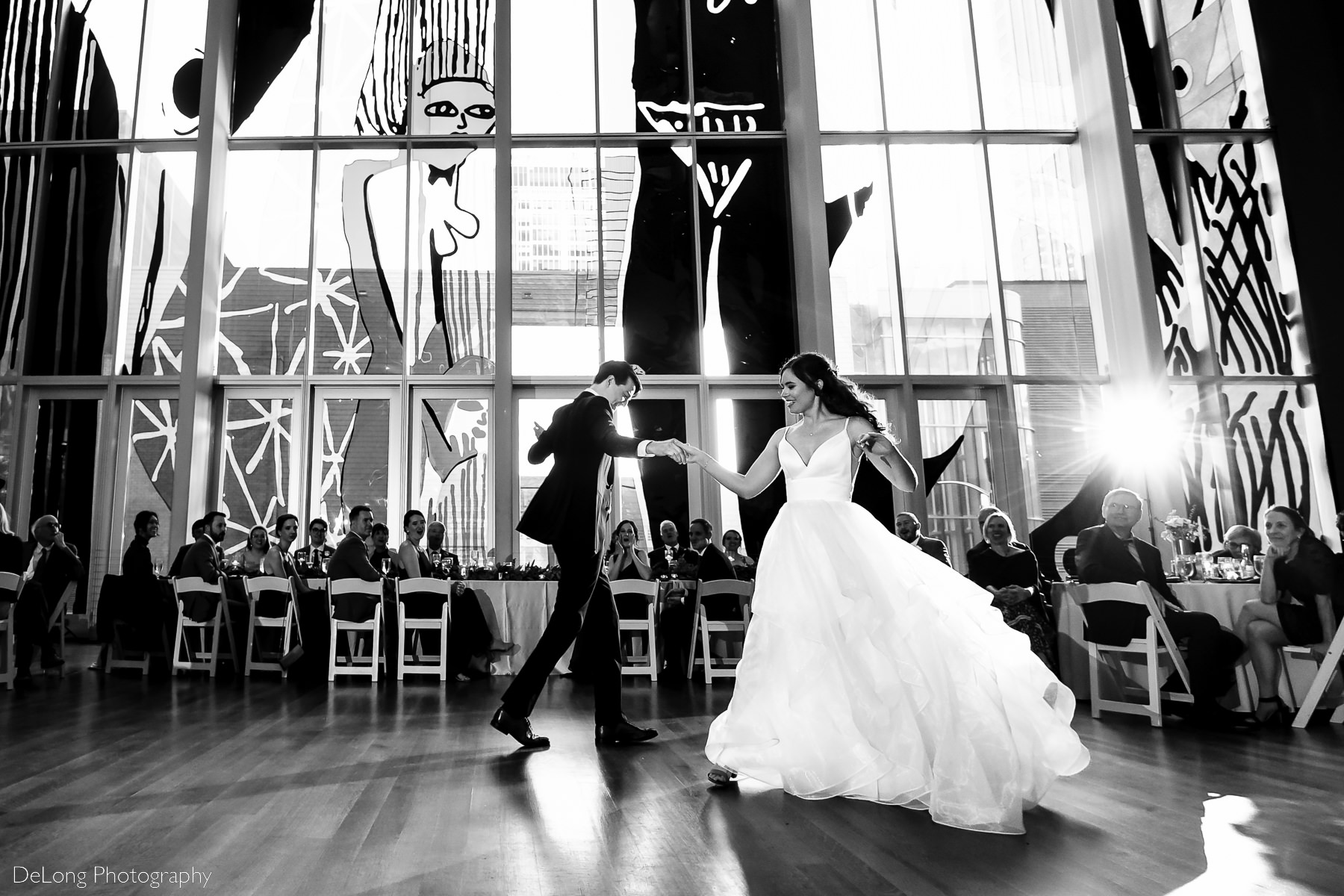 Low angle black and white image of bride and groom performing choreographed dance at the Mint Museum Uptown by Charlotte wedding photographers DeLong Photography
