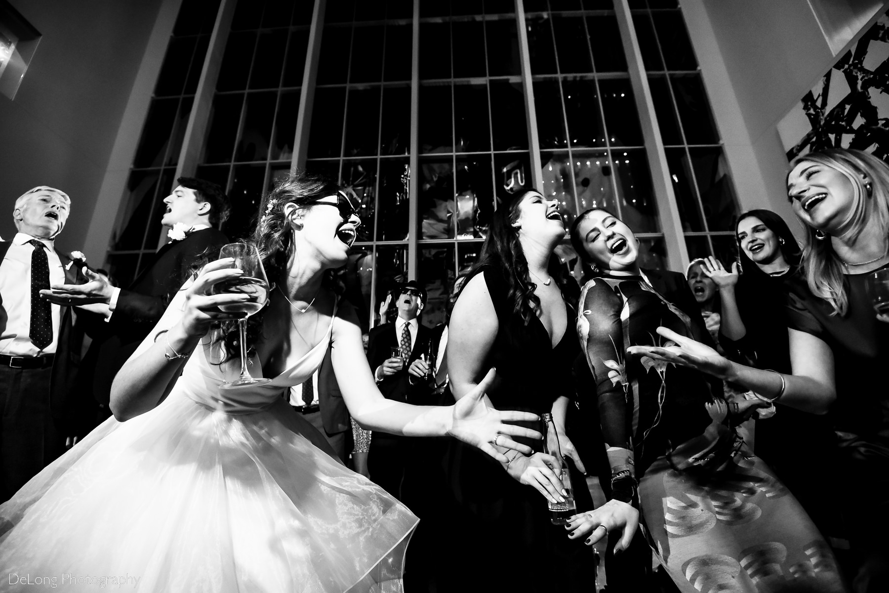 Low angle black and white image of bride and friends singing lyrics to one another by Charlotte wedding photographers DeLong Photography