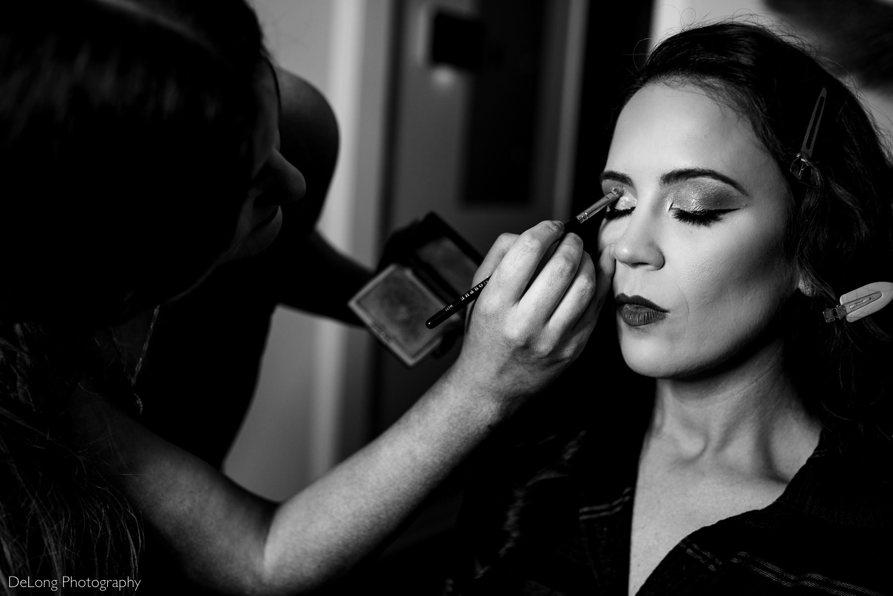 black and white photograph of bride having her eye makeup done by Charlotte wedding photographers DeLong Photography