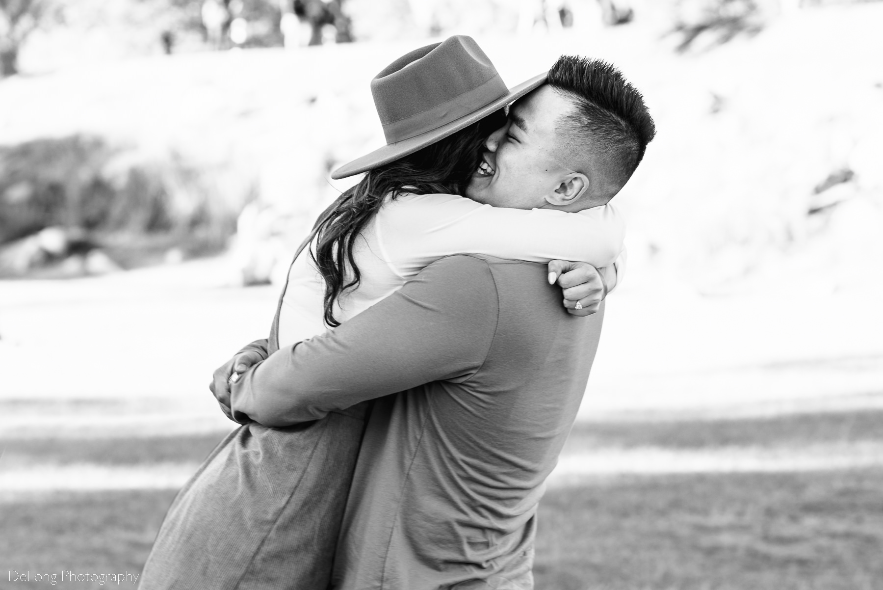 Black and white image of couple embraced in hug following surprise proposal at Riverfront Park in Columbia, SC. Photo by Charlotte wedding photographers DeLong Photography.