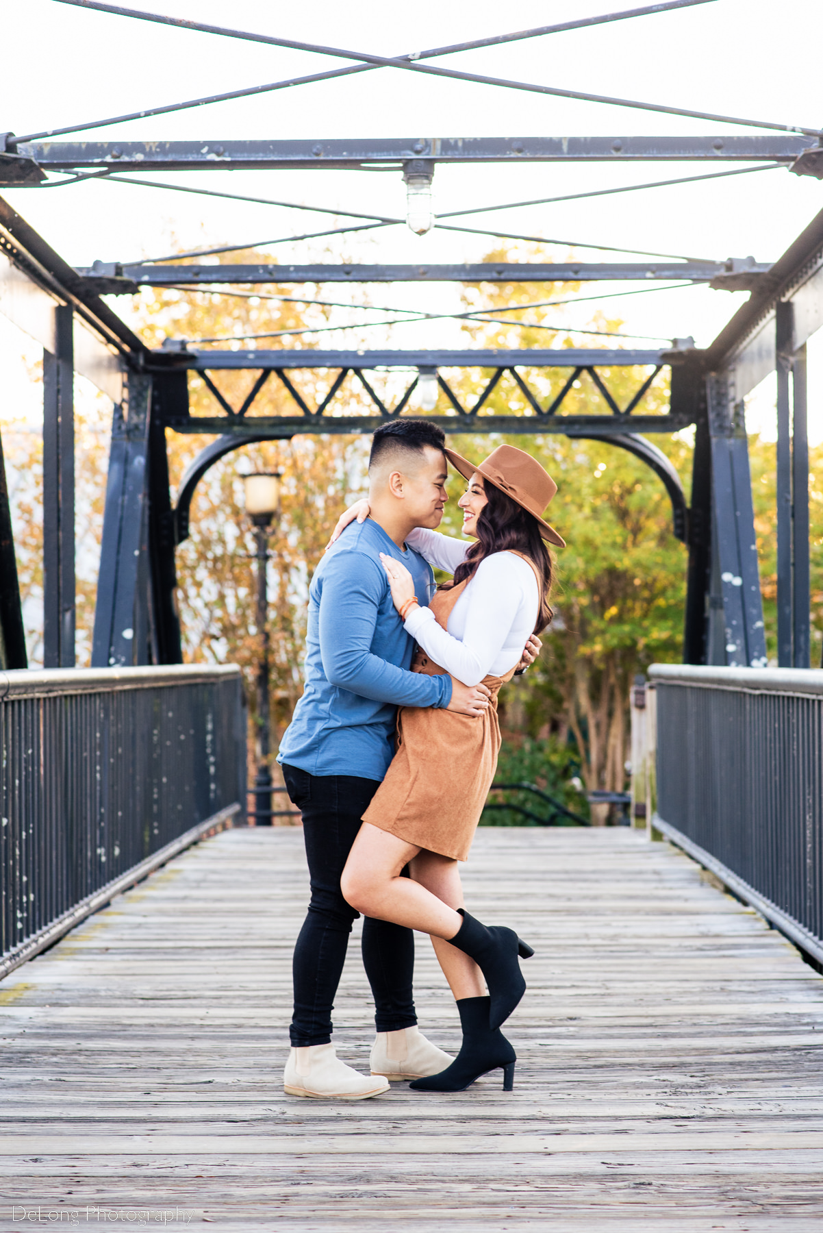 Couple on bridge, smiling with arms around one another at Riverfront Park in Columbia, SC. Photo by Charlotte wedding photographers DeLong Photography.