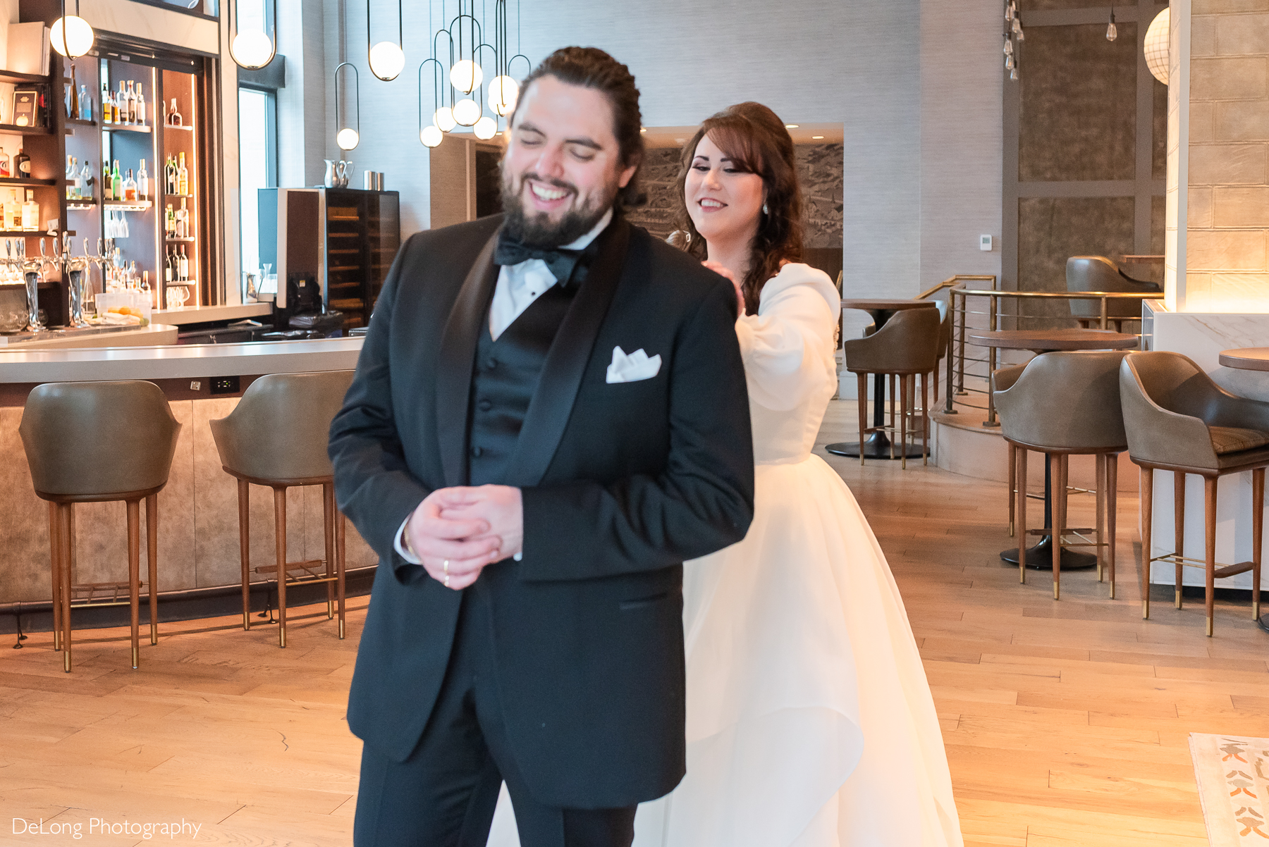 Bride approaching the groom during their first look indoors at the bar on the bottom floor of the Kimpton Hotel Arras. Photograph by Charlotte wedding photographers DeLong Photography.