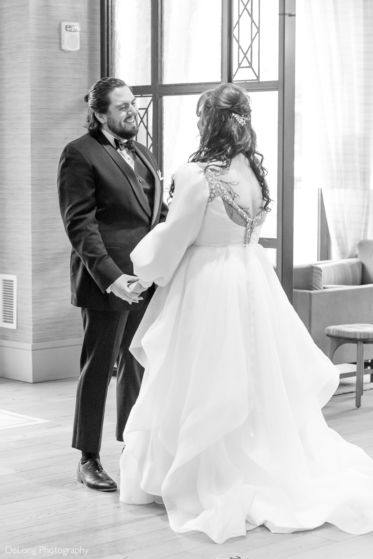 Groom smiling at his bride after turning around and seeing her for the first time during their first look. Photograph by Charlotte wedding photographers DeLong Photography taken in the Kimpton Hotel Arras.