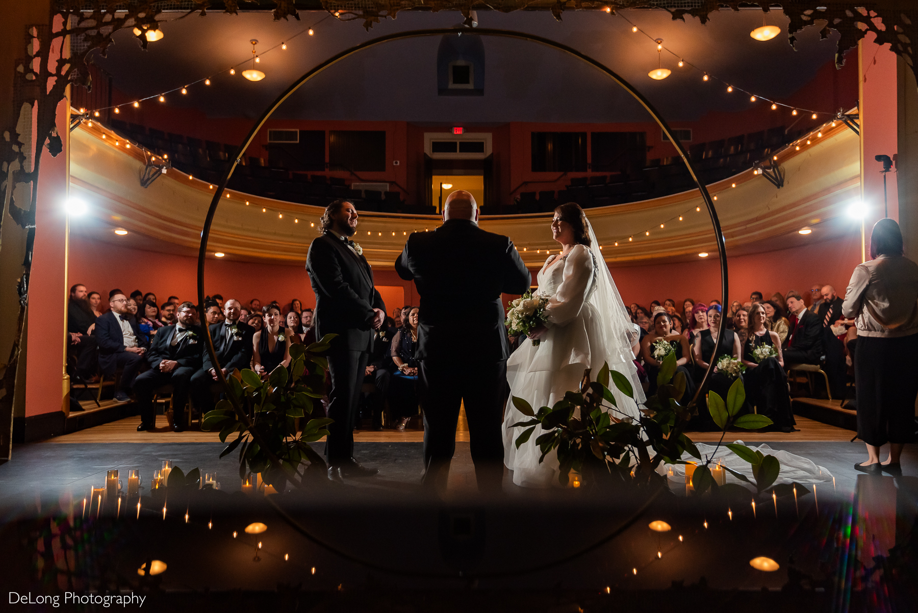 Photograph taken from the stage facing the guests during the wedding ceremony. The hanging fairy lights are reflected in the bottom of the image. Photograph by Charlotte wedding photographers DeLong Photography taken at the Asheville Masonic Temple.