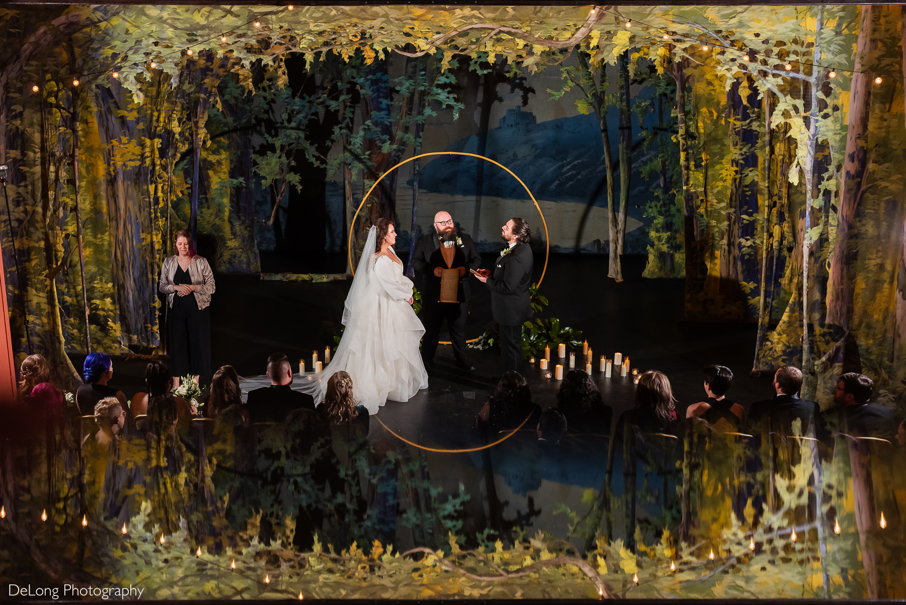 Photograph of the wedding ceremony taken from the balcony of the auditorium. The ceremony on the stage is reflected in the bottom of the image. Photograph by Charlotte wedding photographers DeLong Photography taken at the Asheville Masonic Temple.