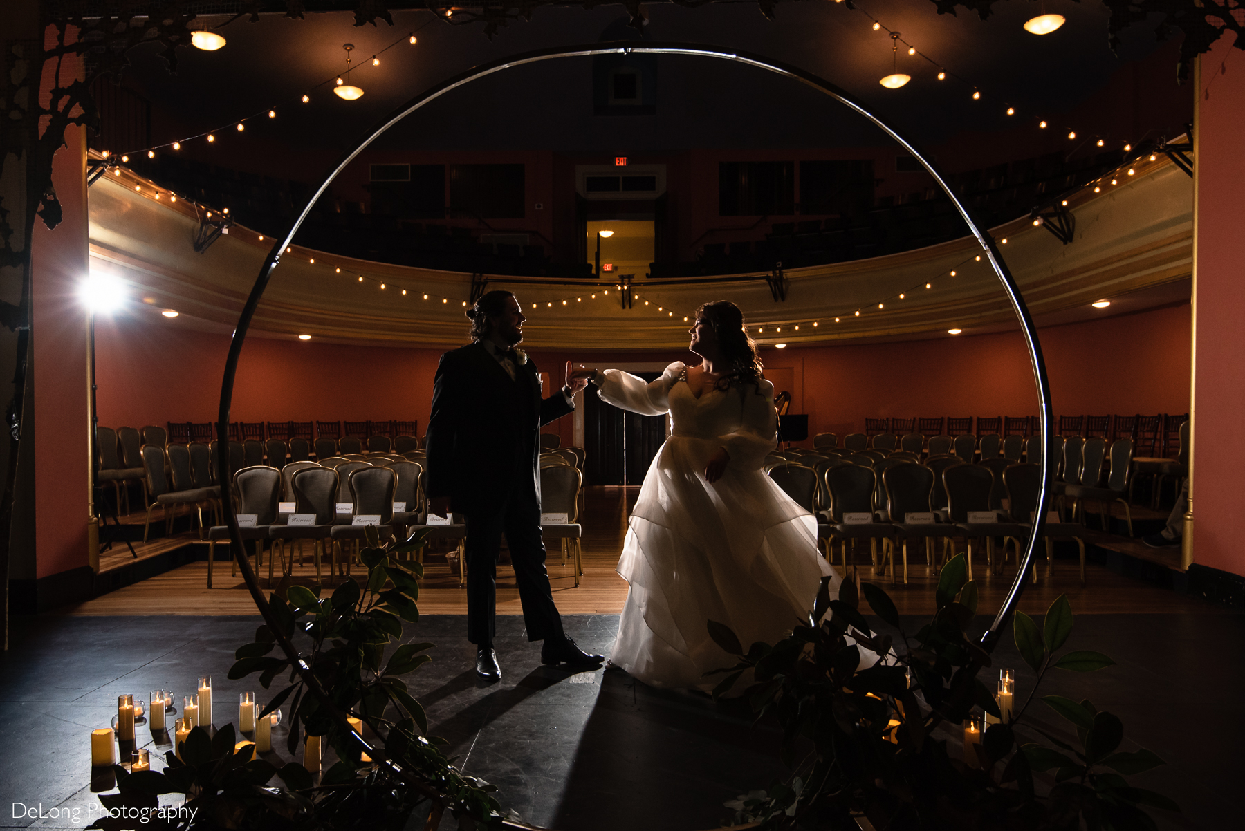 Silhouette of the bride and groom laughing while dancing on the stage of the auditorium. Photograph by Charlotte wedding photographers DeLong Photography taken at the Asheville Masonic Temple.