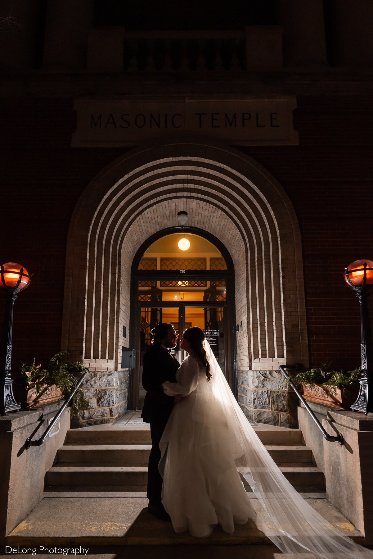 Romantic silhouette of the couple, framed by the arches of the doorway, outside the Asheville Masonic Temple. Photograph by Charlotte wedding photographers DeLong Photography.