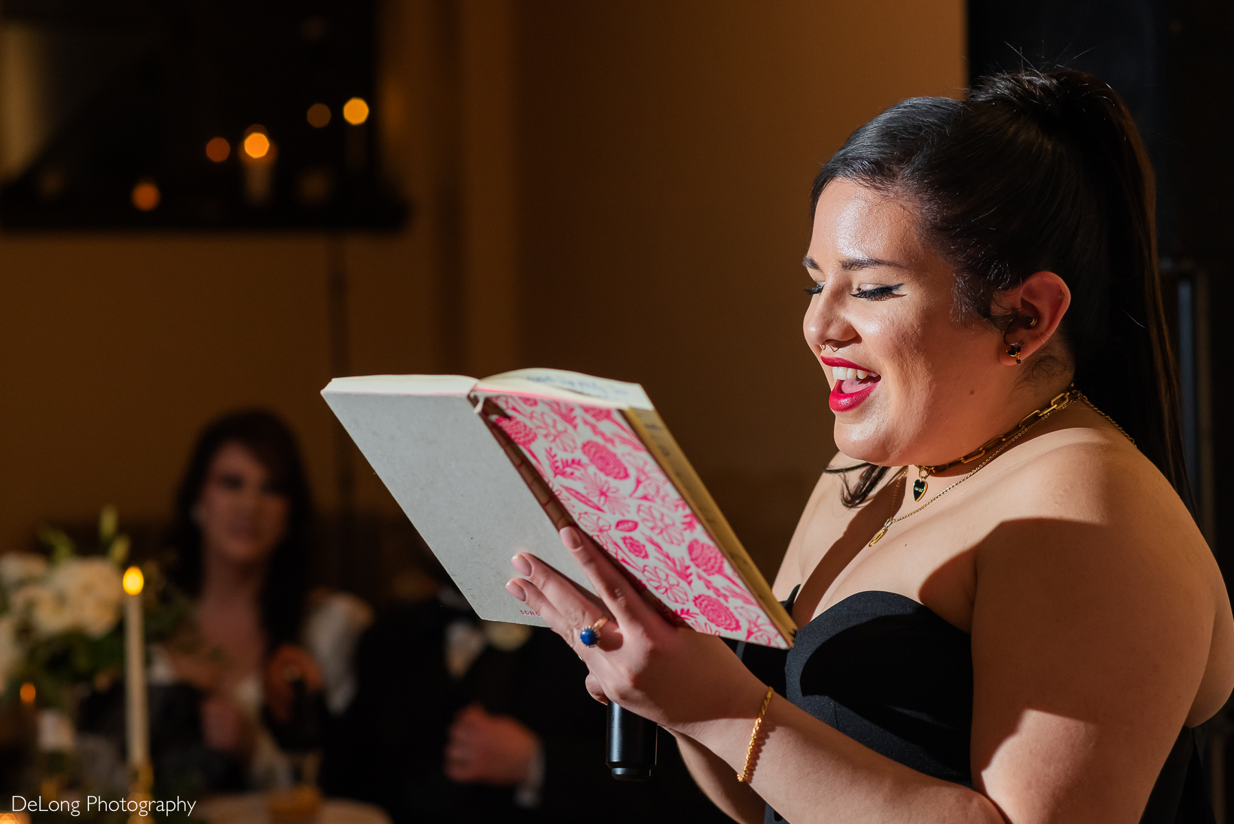 Bride's Maid of Honor smiling while reading her speech during the reception. Photograph by Charlotte wedding photographers DeLong Photography taken at the Asheville Masonic Temple.