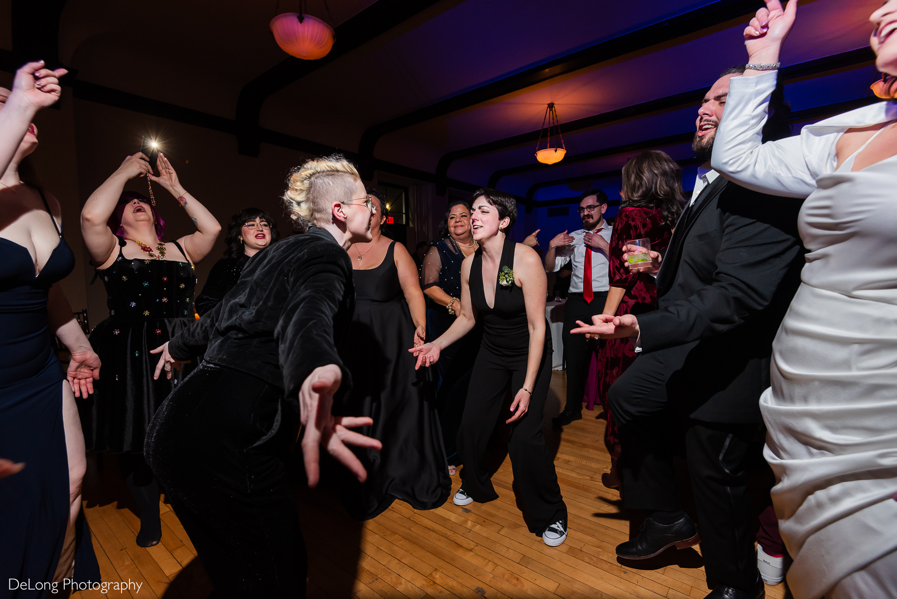 Two guests singing at one another during a dance battle on the dance floor. Photograph by Charlotte wedding photographers DeLong Photography taken at the Asheville Masonic Temple.