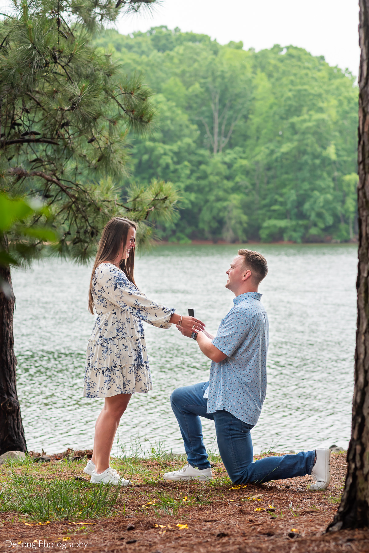 Photograph of man proposing to woman near the water during summertime at Jetton Park. 