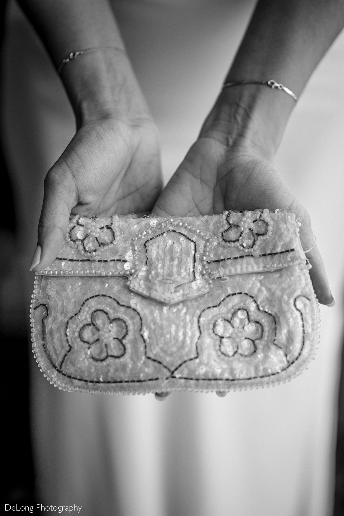 Black and white photograph of a bride gently holding a delicate, beaded clutch—an heirloom passed down from her grandmother. Captured at the Kimpton Tryon Park Hotel by DeLong Photography.