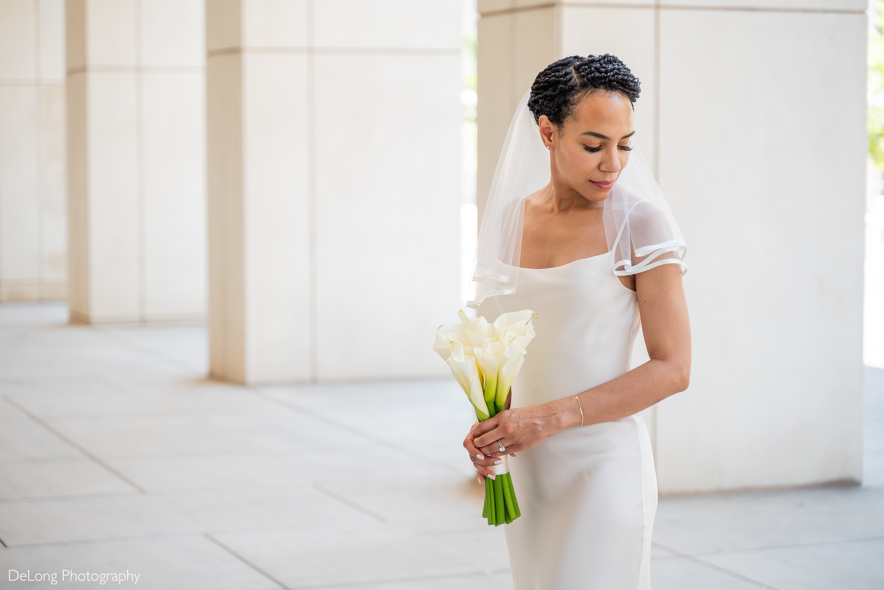 Elegant bride holding a bouquet of white calla lilies during her Uptown Charlotte elopement, photographed by DeLong Photography—a luxury wedding photographer in Charlotte, NC, specializing in sophisticated, modern, and editorial-style wedding portraits for stylish couples.