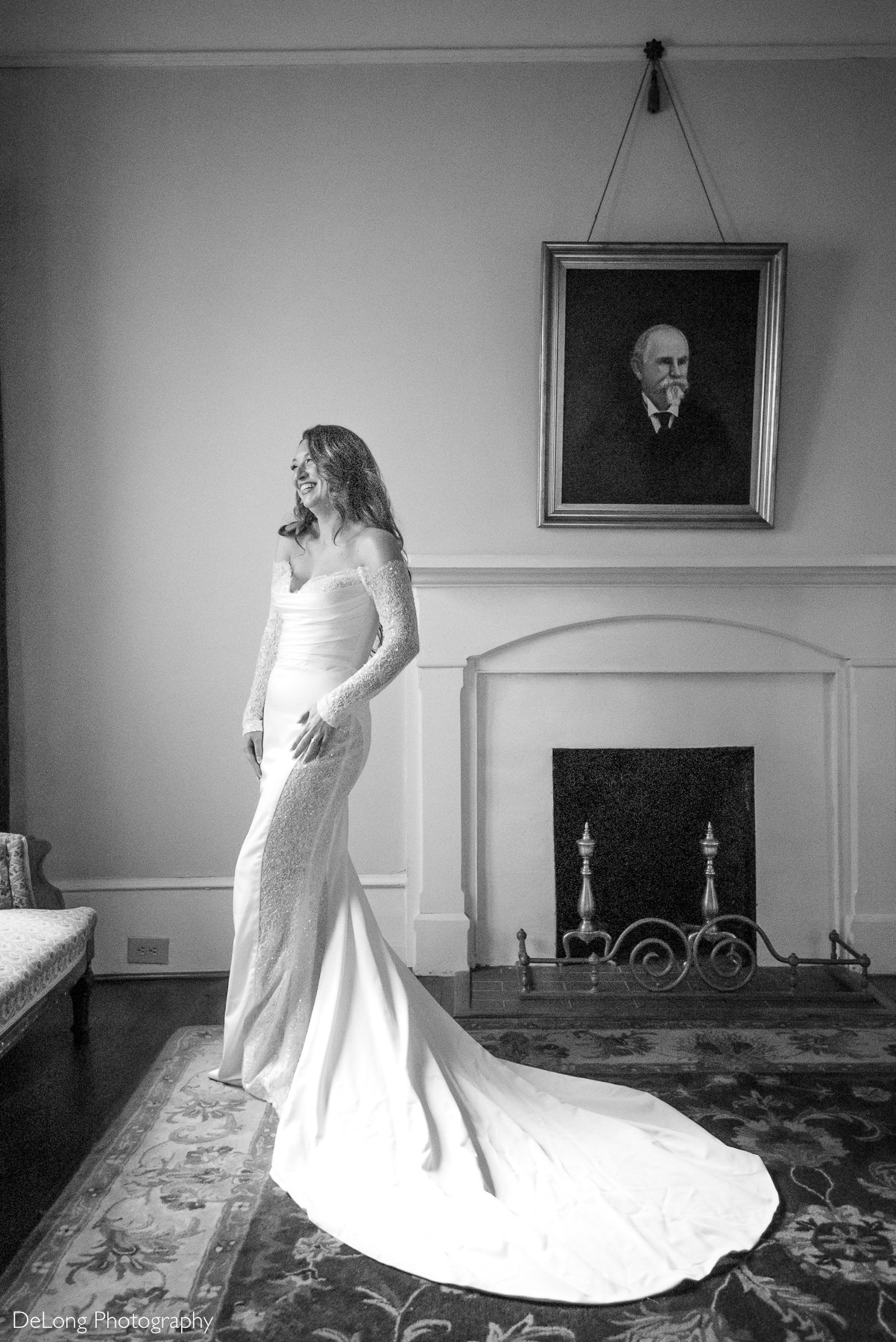 Bride wearing an off-the-shoulder gown with beaded sleeves smiles during a bridal portrait session at The White Home in Rock Hill, SC, captured by DeLong Photography.