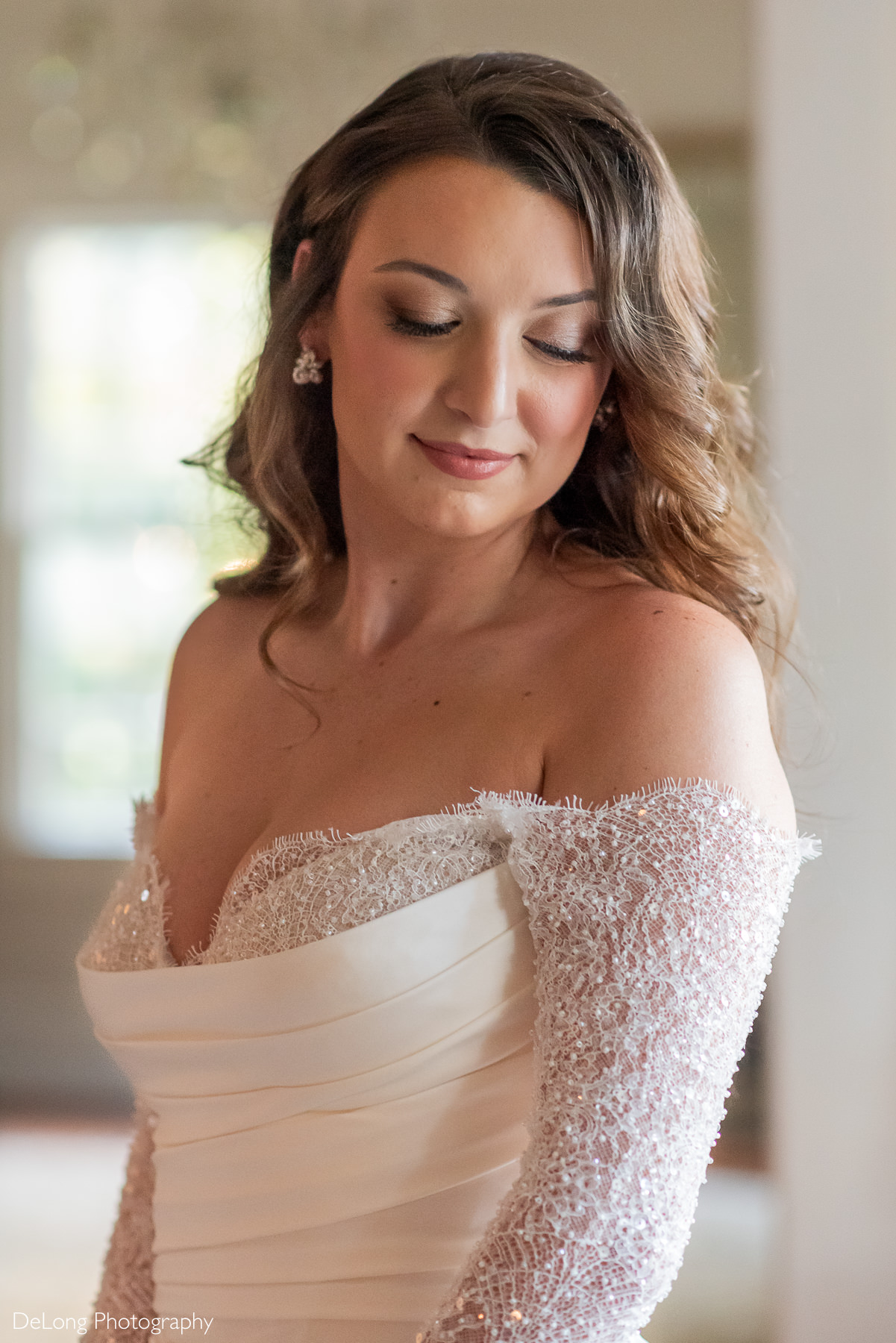 Close-up of bride Carrie looking downward in an off-the-shoulder beaded sleeve wedding gown during her bridal portrait session at The White Home in Rock Hill, SC, photographed by DeLong Photography.