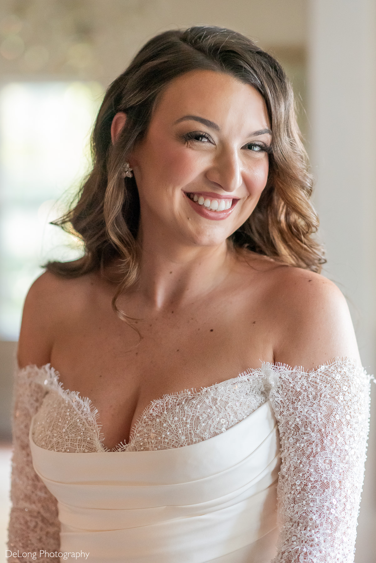 Close-up of bride Carrie smiling in an off-the-shoulder beaded sleeve wedding gown during her bridal portrait session at The White Home in Rock Hill, SC, photographed by DeLong Photography.