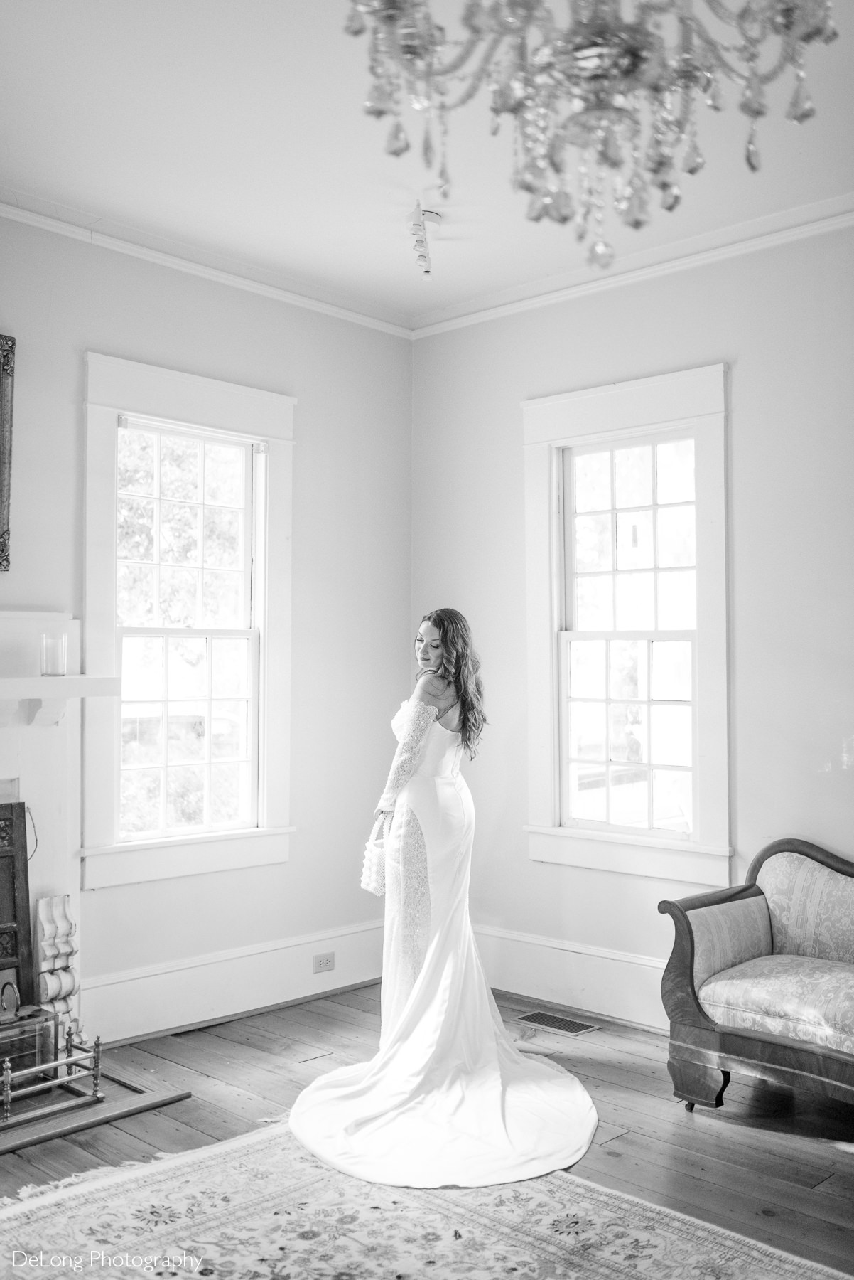 Elegant bridal portrait at The White Home in Rock Hill, SC, featuring a bride in an off-the-shoulder lace wedding gown with a dramatic train, photographed by DeLong Photography in a bright, historic parlor with vintage decor.