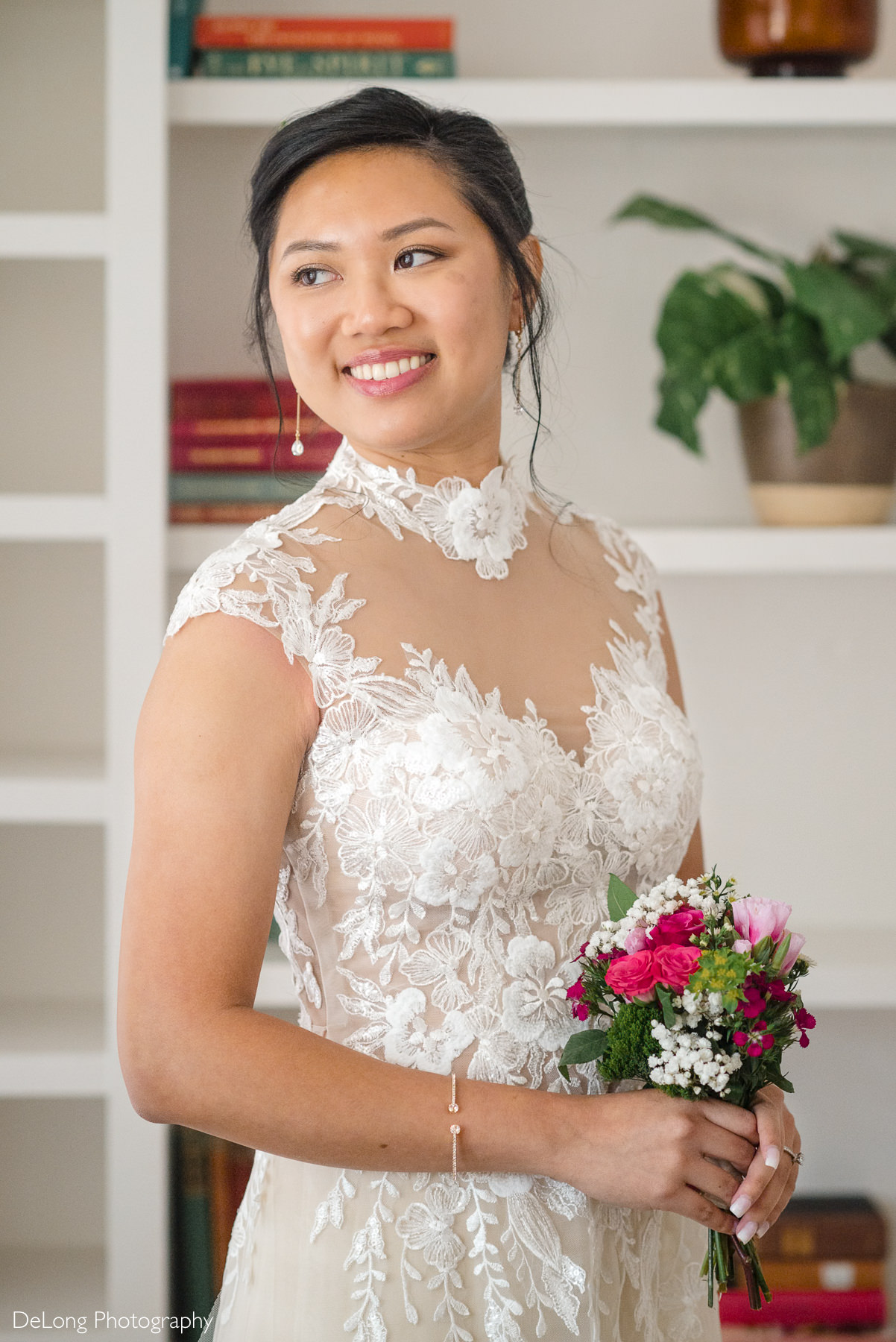 Bride holding a vibrant pink and white bouquet, wearing an Áo Dài-inspired lace jumpsuit for her fall elopement at the Wake County Courthouse in Raleigh, North Carolina, captured by DeLong Photography.
